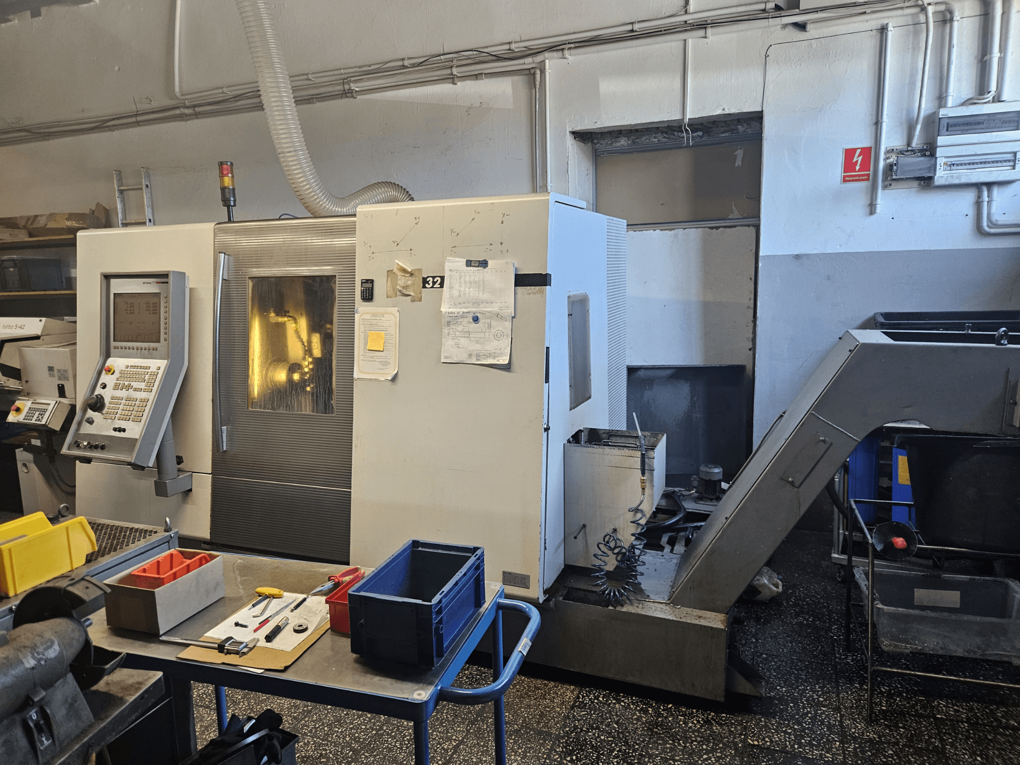 Daugiasvirtės tekinimo staklės DMG GILDEMEISTER Sprint 32 linear, vaizdas iš priekio dirbtuvėse, matomas valdymo skydelis ir įrankiai.