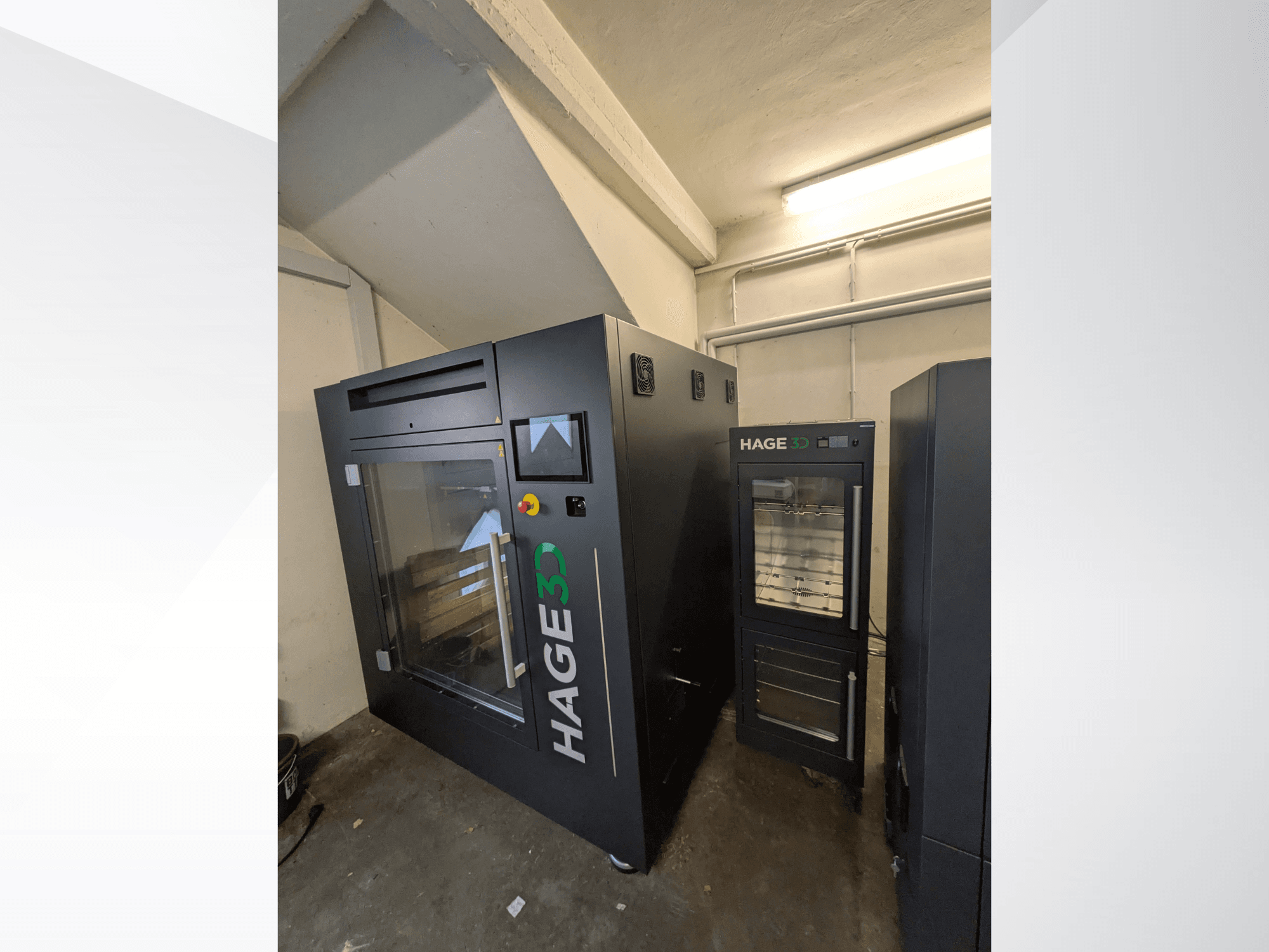 „HAGE 3D Precision One“ plastikinis 3D spausdintuvas, vaizduojamas iš kampo, su permatomomis durelėmis ir valdymo skydeliu, šalia jo – daiktų laikymo vieta.