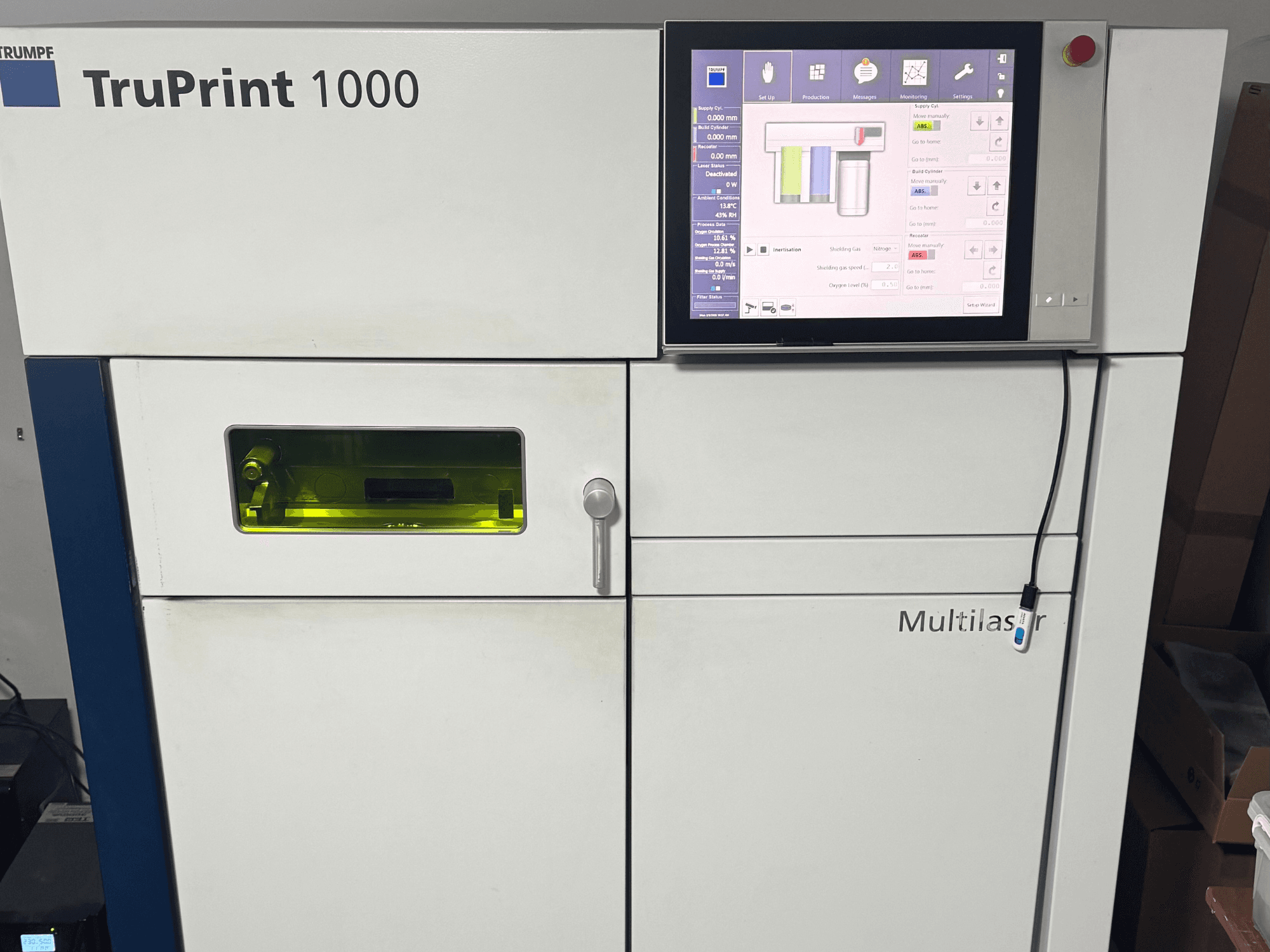 "Trumpf" "TruPrint 1000", vaizdas iš priekio, su skaitmeniniu valdymo skydeliu ir permatomu kontrolės langu, skirtu stebėti.