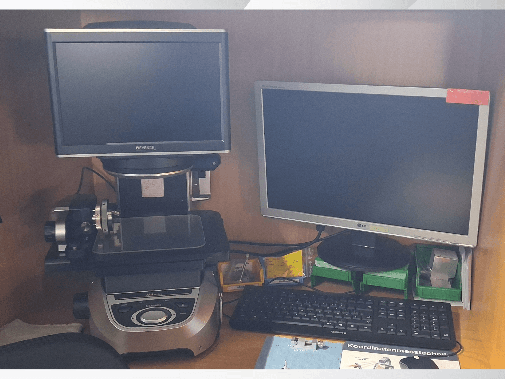 "Keyence" matavimo sistema su dviem monitoriais (vienu LG, kitu "Keyence") ir klaviatūra, žiūrint iš priekio.