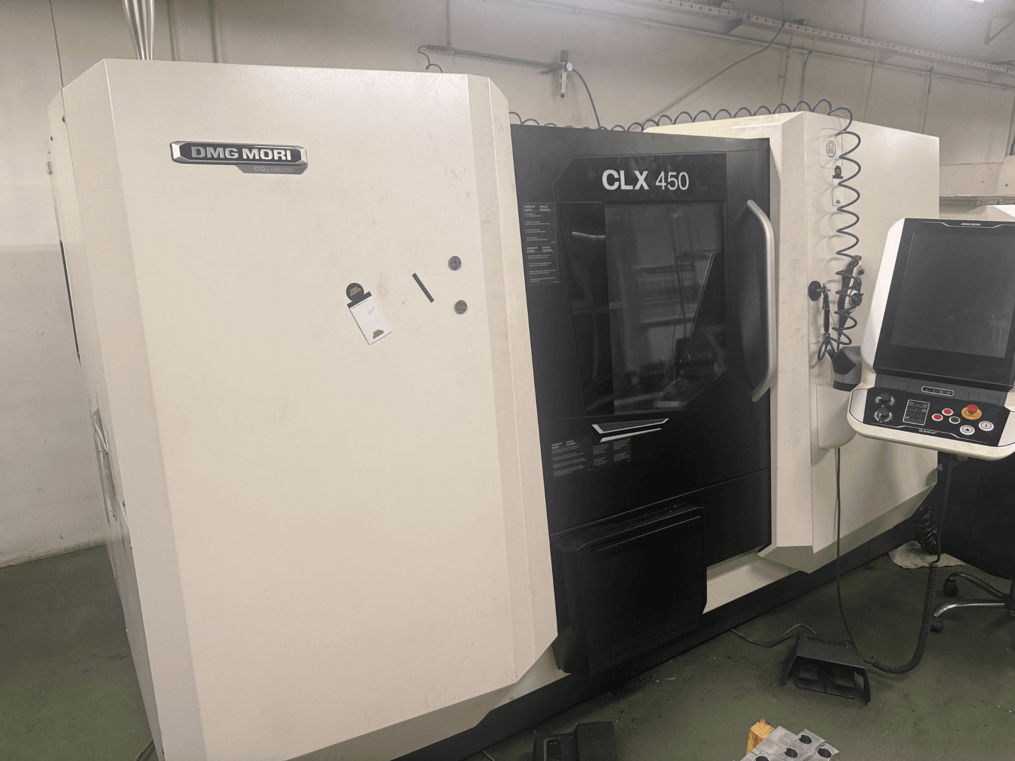 DMG MORI CLX 450 CNC staklės, šoninis vaizdas su valdymo skydeliu, matomais valdymo mygtukais ir švaria darbo vieta.