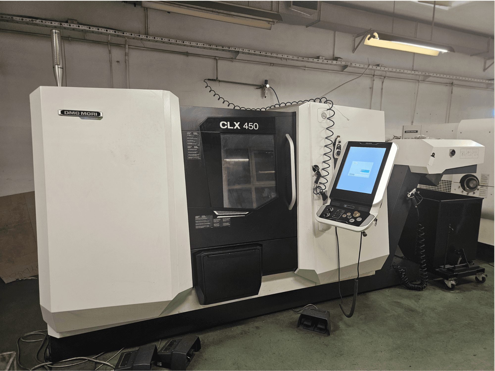 DMG MORI CLX 450 CNC staklės su valdymo pultu ir jutiklinio ekrano ekranu dirbtuvių aplinkoje iš priekio.