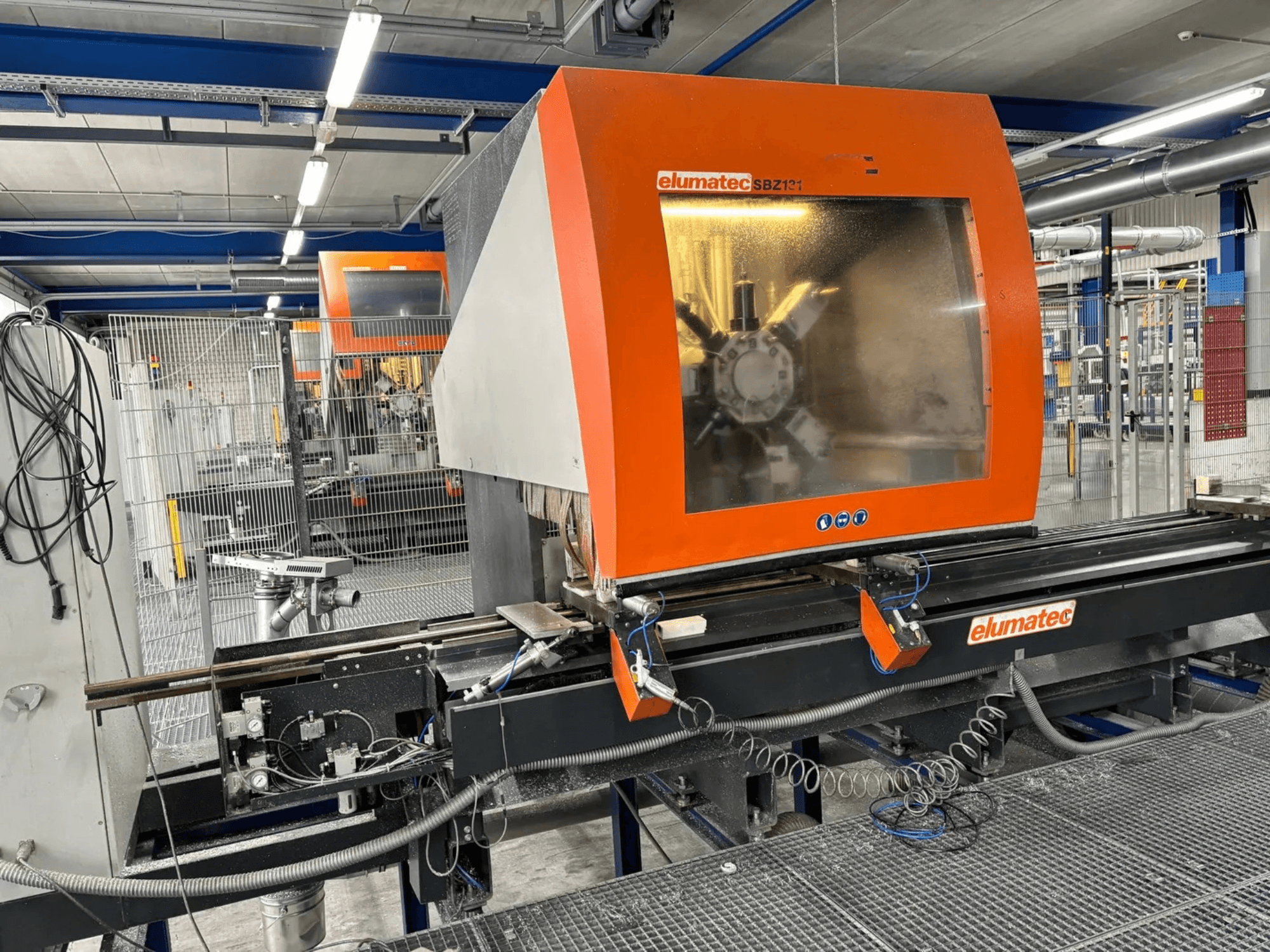 "Elumatec SBZ 131" vertikalusis apdirbimo centras, priekinis vaizdas, kuriame matyti valdymo skydelis, mašinų detalės ir supanti darbo aplinka.