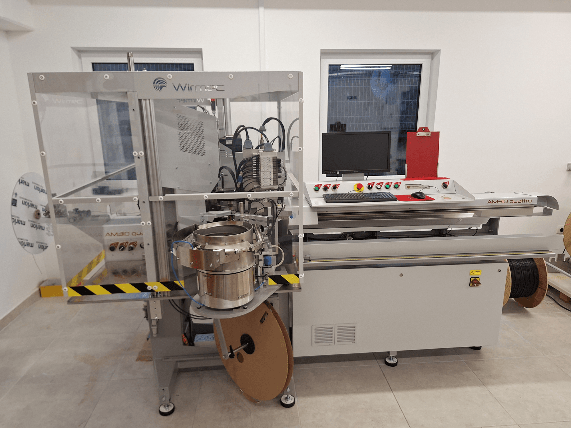 WIRMEC AM310-117 staklės, vaizdas iš priekio, su valdymo pultu, kompiuteriu ir nerūdijančio plieno komponentais, išdėstytomis darbo vietoje.