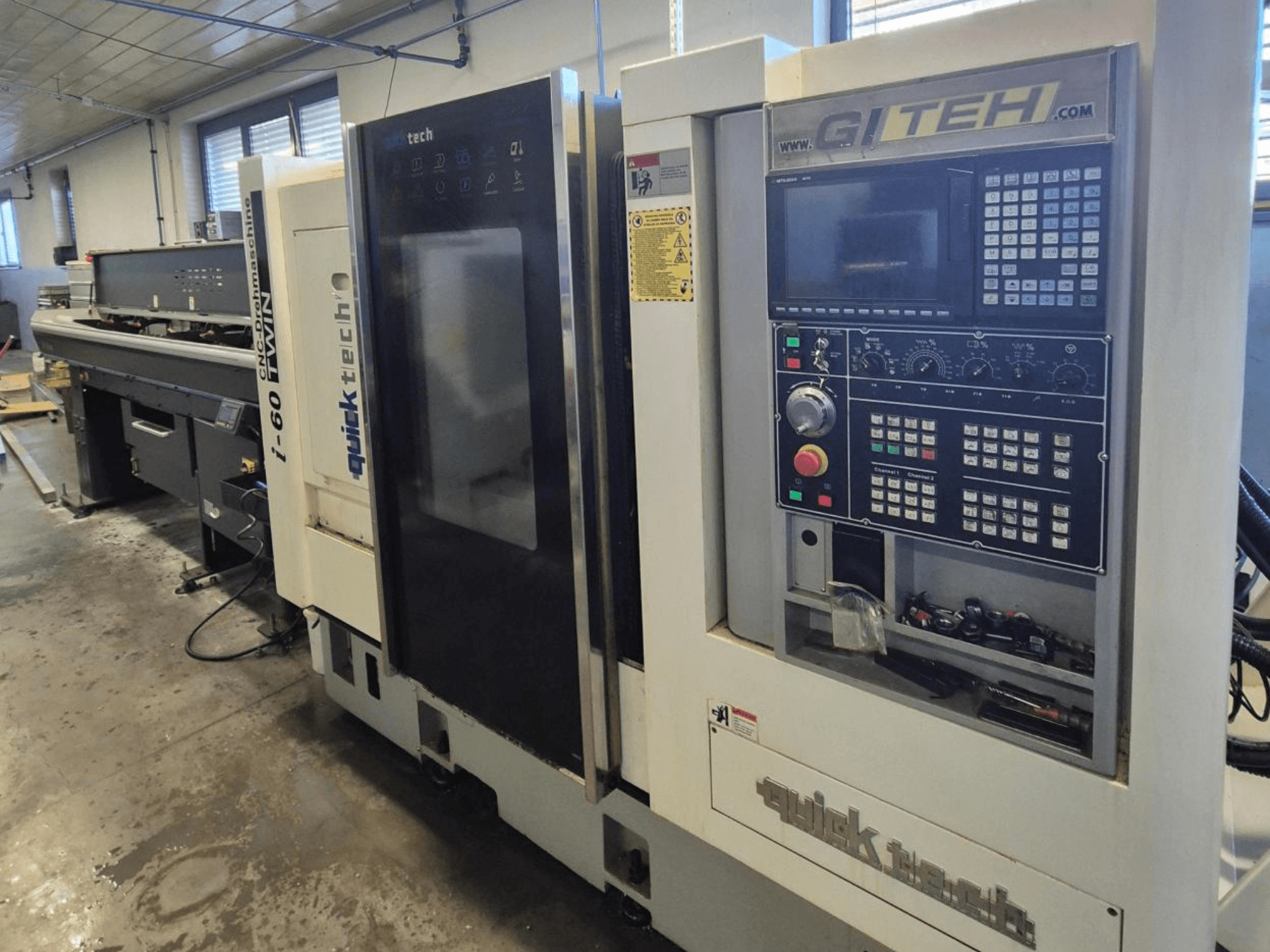 "Quick Tech i-60" dvigubos CNC staklės, vaizdas iš priekio, su GITEH valdymo skydeliu ir valdymo mygtukais, dirbtuvėse.