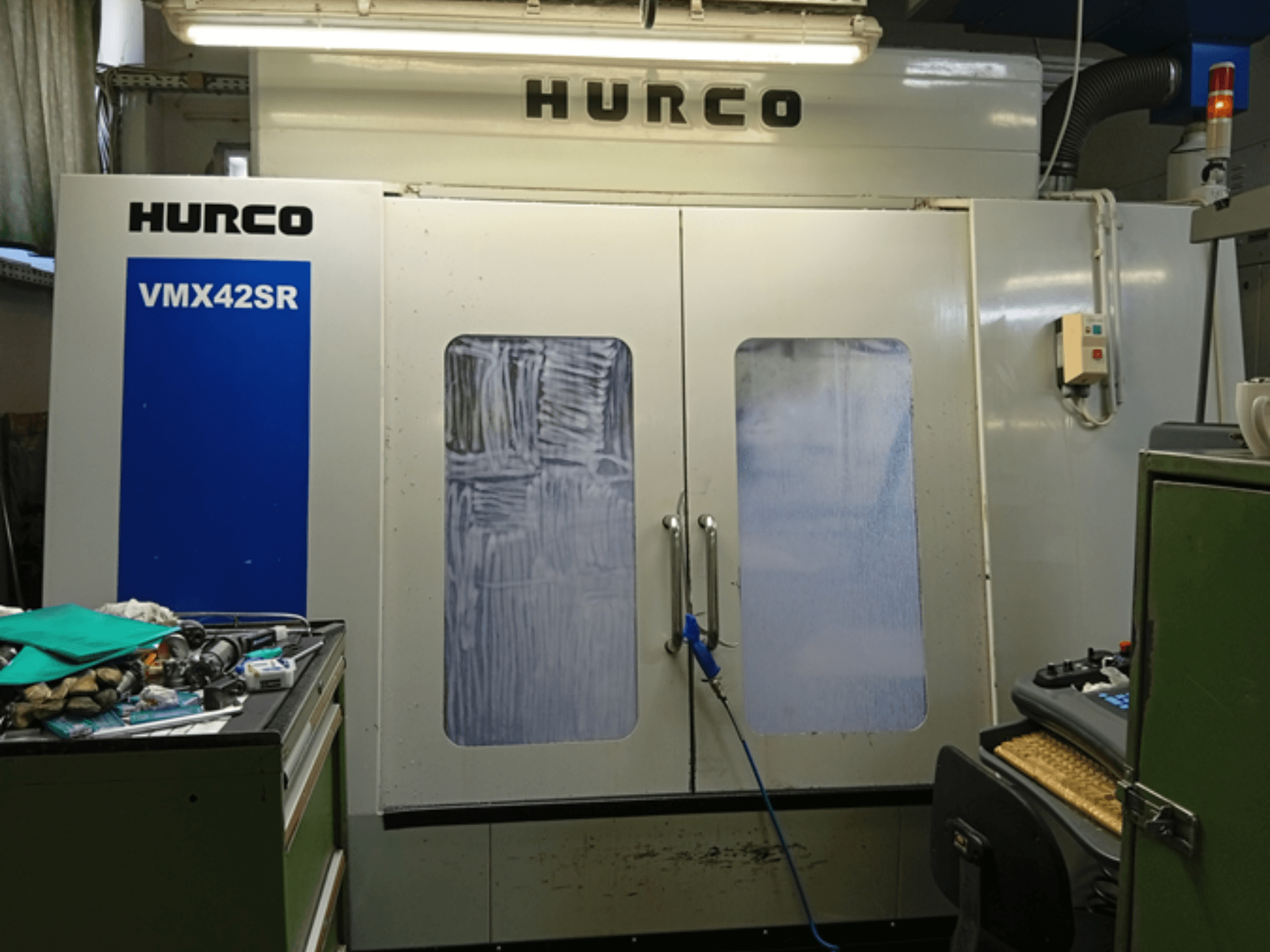 Vertikalaus apdirbimo centro "Hurco VMX 42SR" vaizdas iš priekio: mėlynas skydelis, valdymo sąsaja ir švari darbo erdvė.