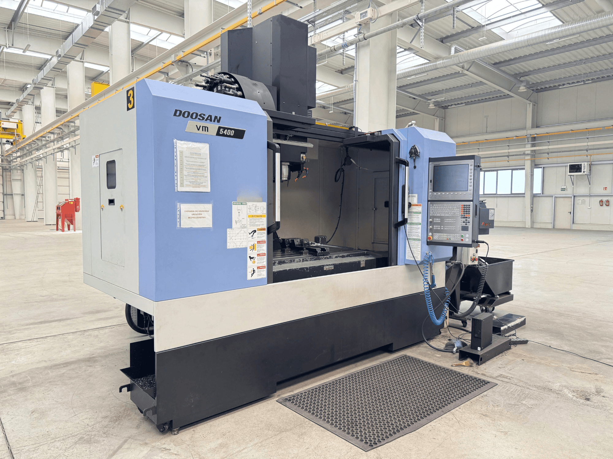 DOOSAN VM 5400 vertikalusis apdirbimo centras, priekinis vaizdas, rodantis valdymo skydelį ir darbo zoną erdvioje pramoninėje aplinkoje.