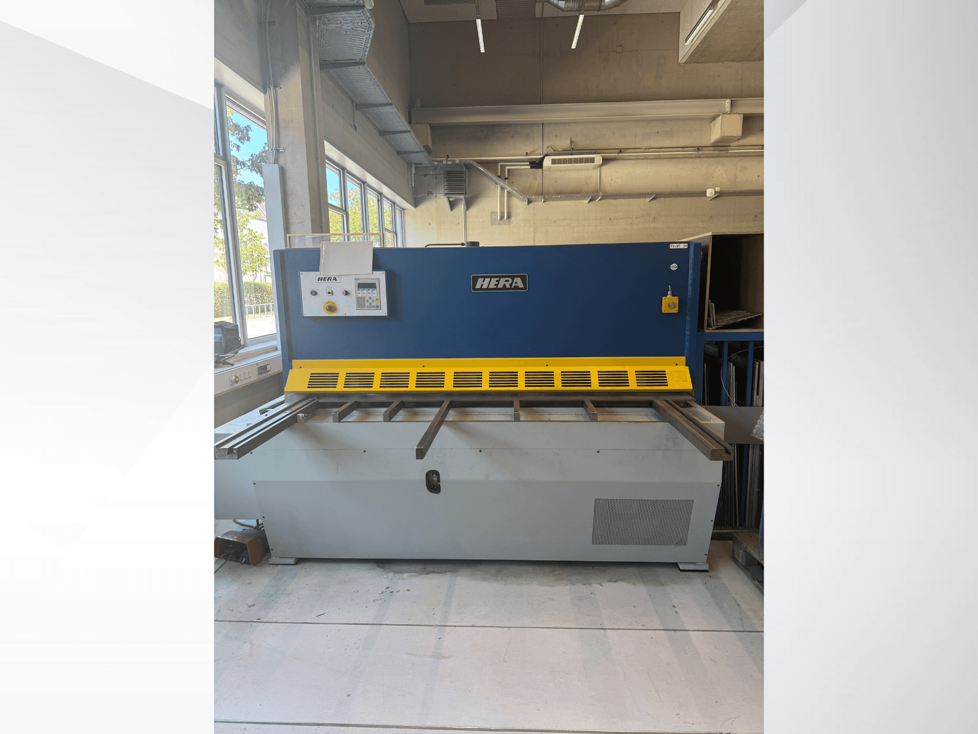 HERA TS 2000x6 hidraulinės kirpimo staklės, vaizdas iš priekio; mėlynos ir geltonos spalvų, su valdymo pultu ir pjovimo stalu.
