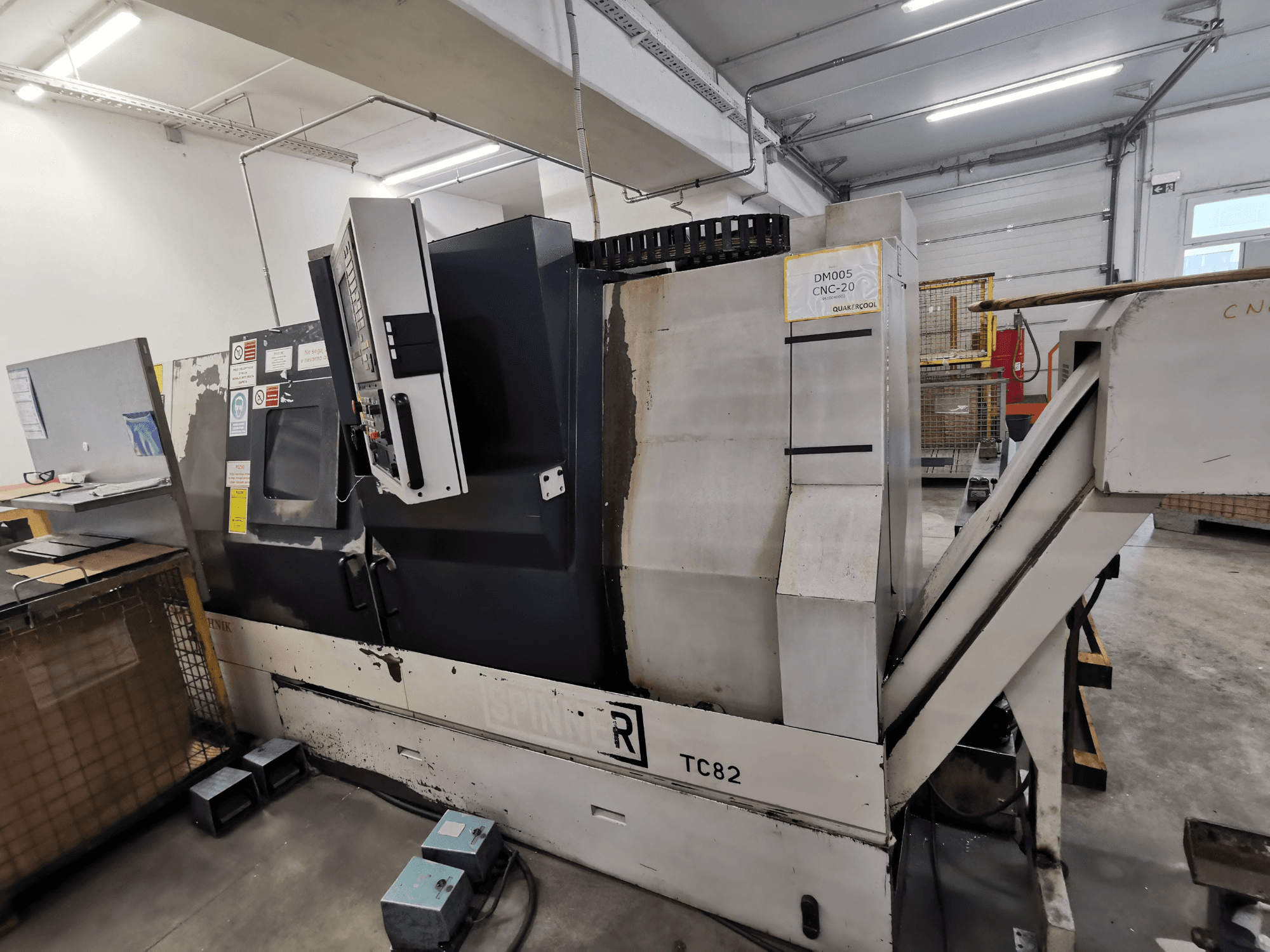 CNC staklės, prekės ženklas Spinner, modelis TC82, šoninis vaizdas, kuriame matomas valdymo skydelis ir laužo šalinimo latakas dirbtuvėse.