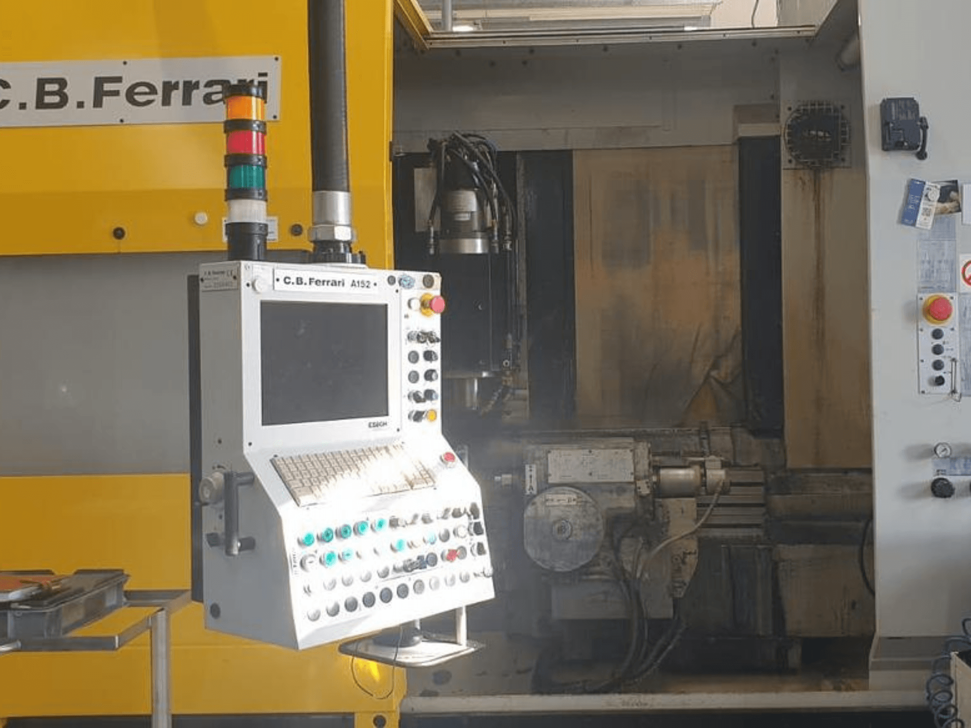 C.B. Ferrari A152 vertikaliojo apdirbimo centro priekinis vaizdas, kuriame matyti valdymo skydelis su mygtukais ir mašinos variklio komponentai.