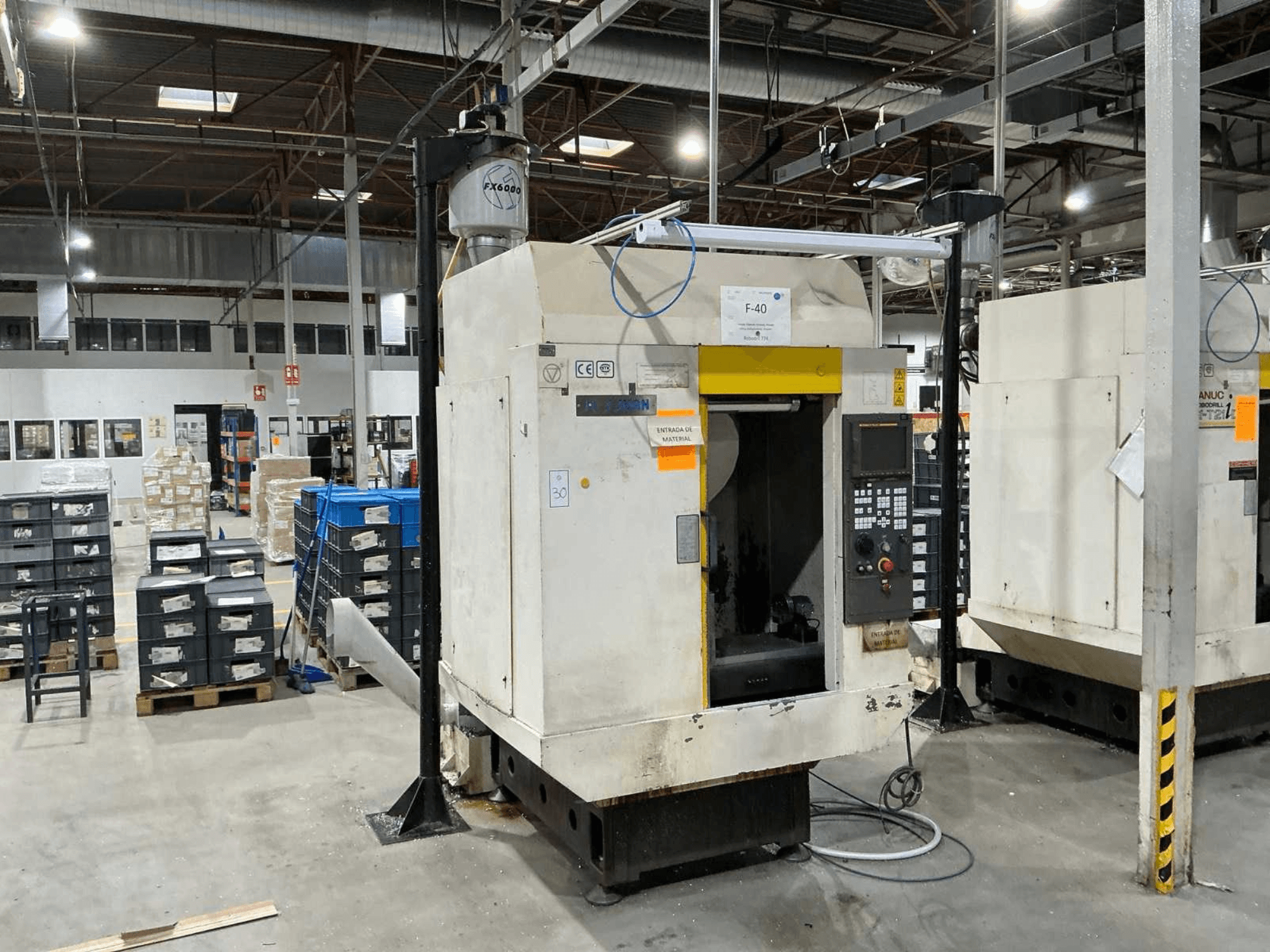 FANUC ROBODRILL α-T21iD, vertikalaus apdirbimo centro vaizdas iš priekio pramoninėje aplinkoje, matomos valdymo skydelio detalės.