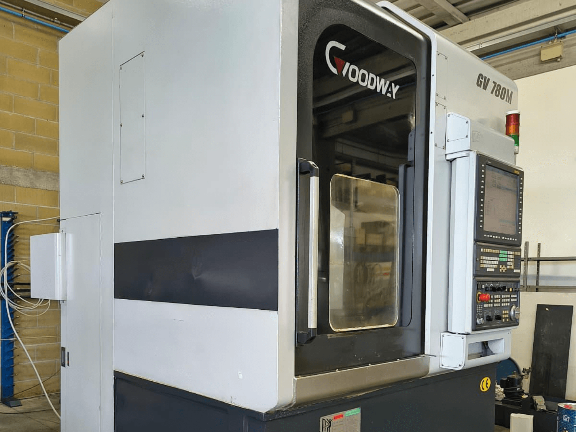 "Goodway GV 780 M" vertikaliojo tekinimo staklės, šoninis vaizdas, kuriame matomas valdymo skydelis, saugos funkcijos ir švarus išorės dizainas.