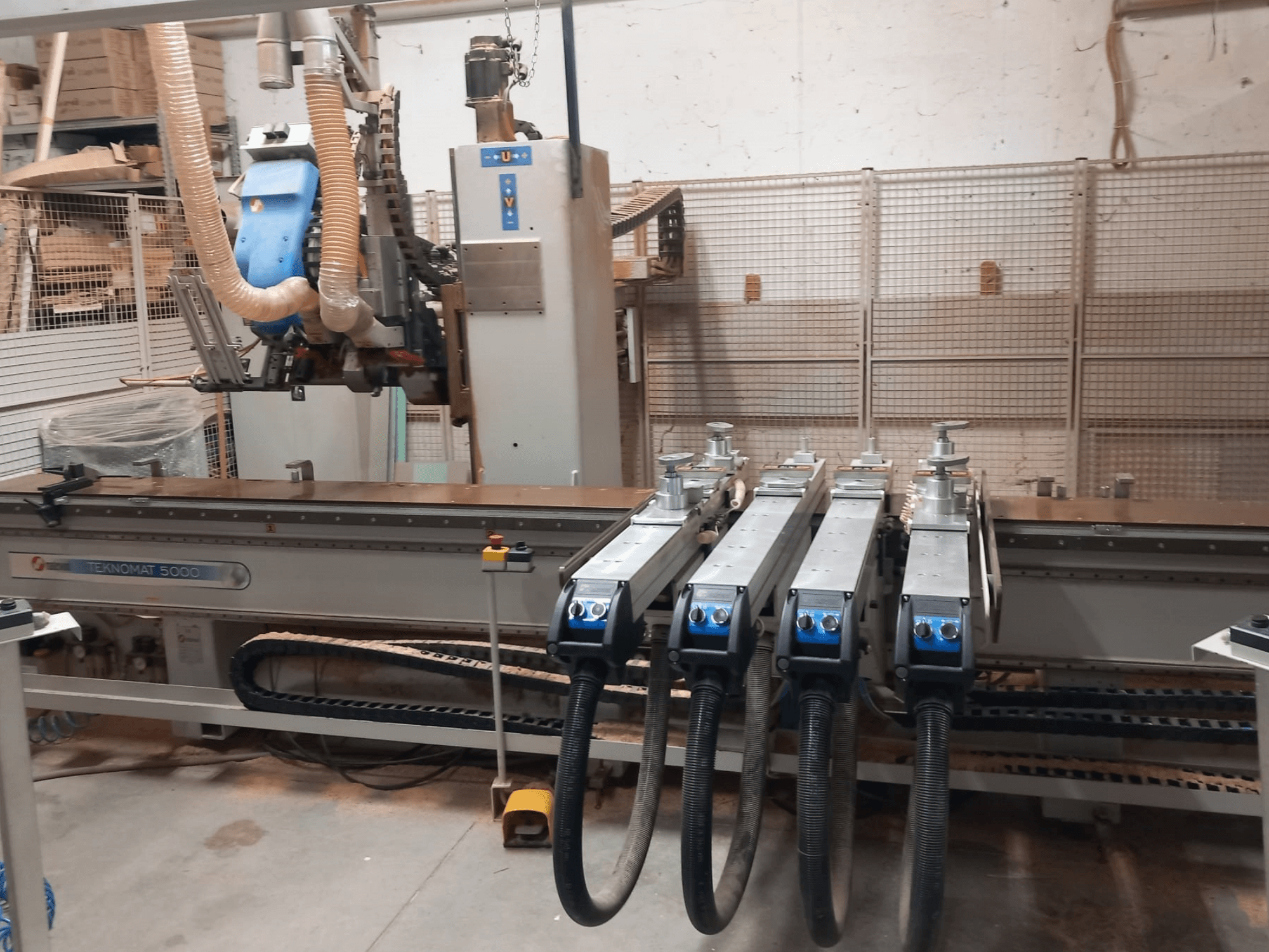 CNC medžio apdirbimo centras „MASTERWOOD TEKNOMAT 5000“, vaizdas iš priekio, kuriame matoma įrankių galvutė ir keli siurbimo žarnai.