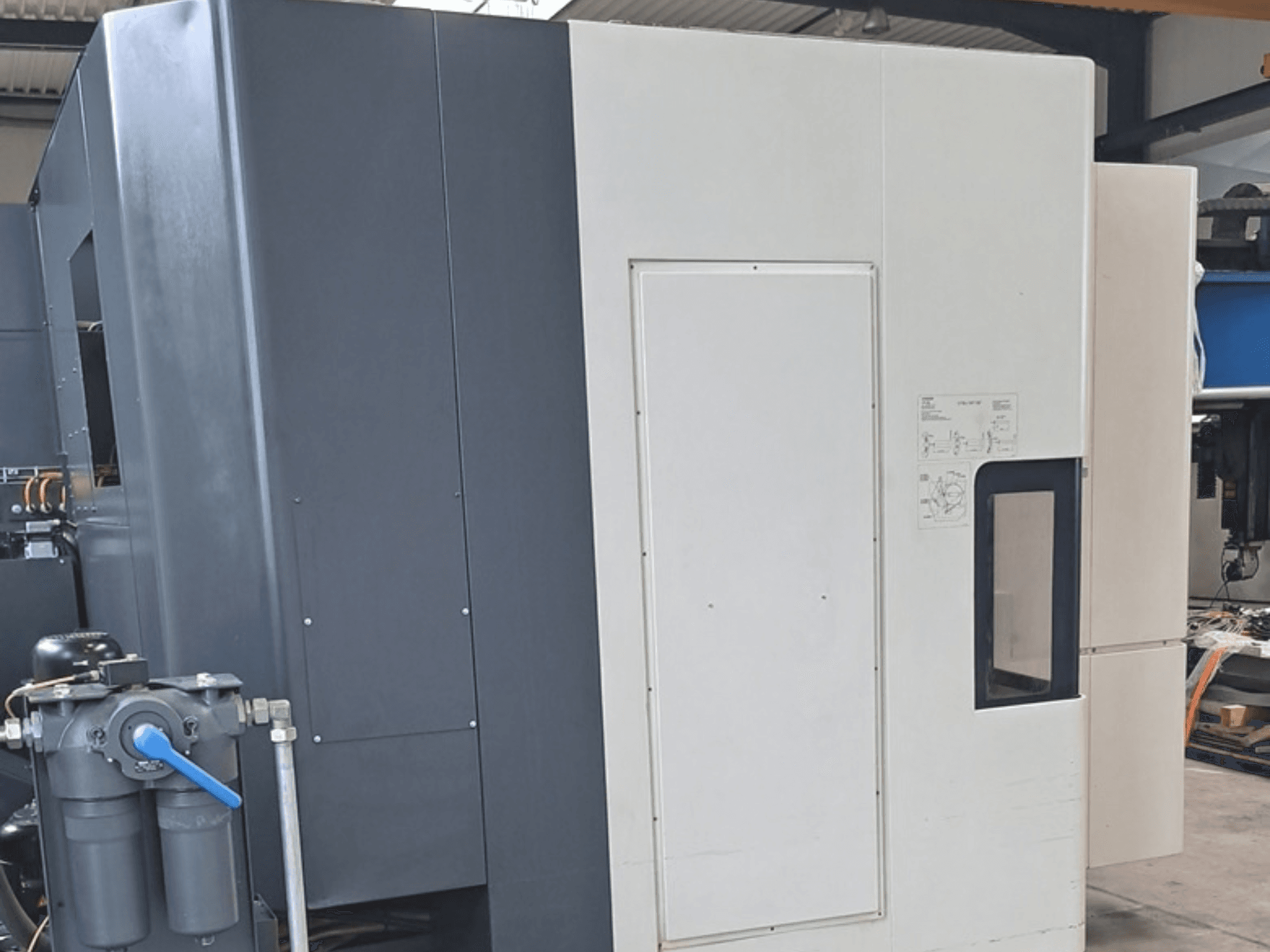 DMG MORI NHX5000 horizontalus apdirbimo centras, šoninis vaizdas, kuriame matomas valdymo pultas ir mechaninės detalės.