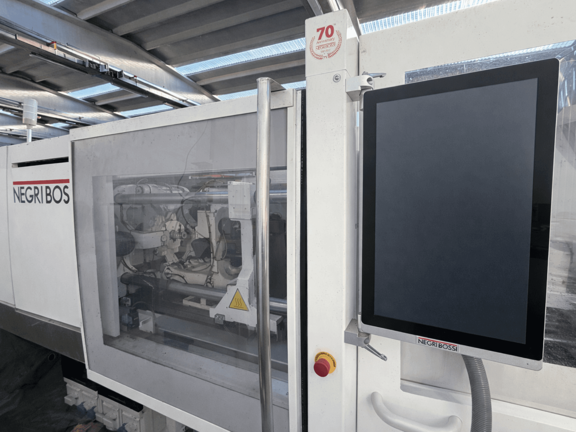 "Negri Bossi ELE 80" elektrinė įpurškimo mašina, vaizdas iš priekio su valdymo ekranu ir matomais vidiniais komponentais.