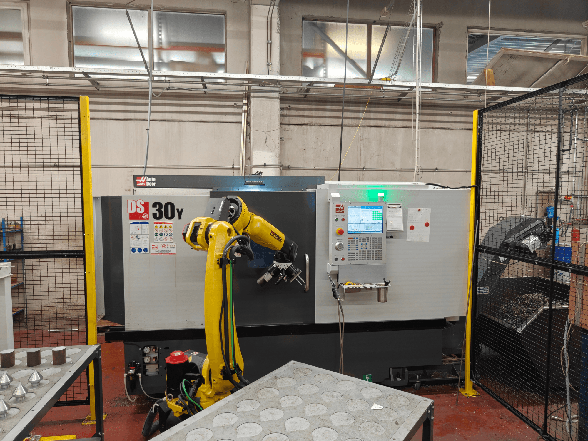 HAAS DS30Y horizontalusis tekinimo staklės su robotine ranka, vaizdas iš priekio, kuriame matomas valdymo pultas ir darbo erdvė.