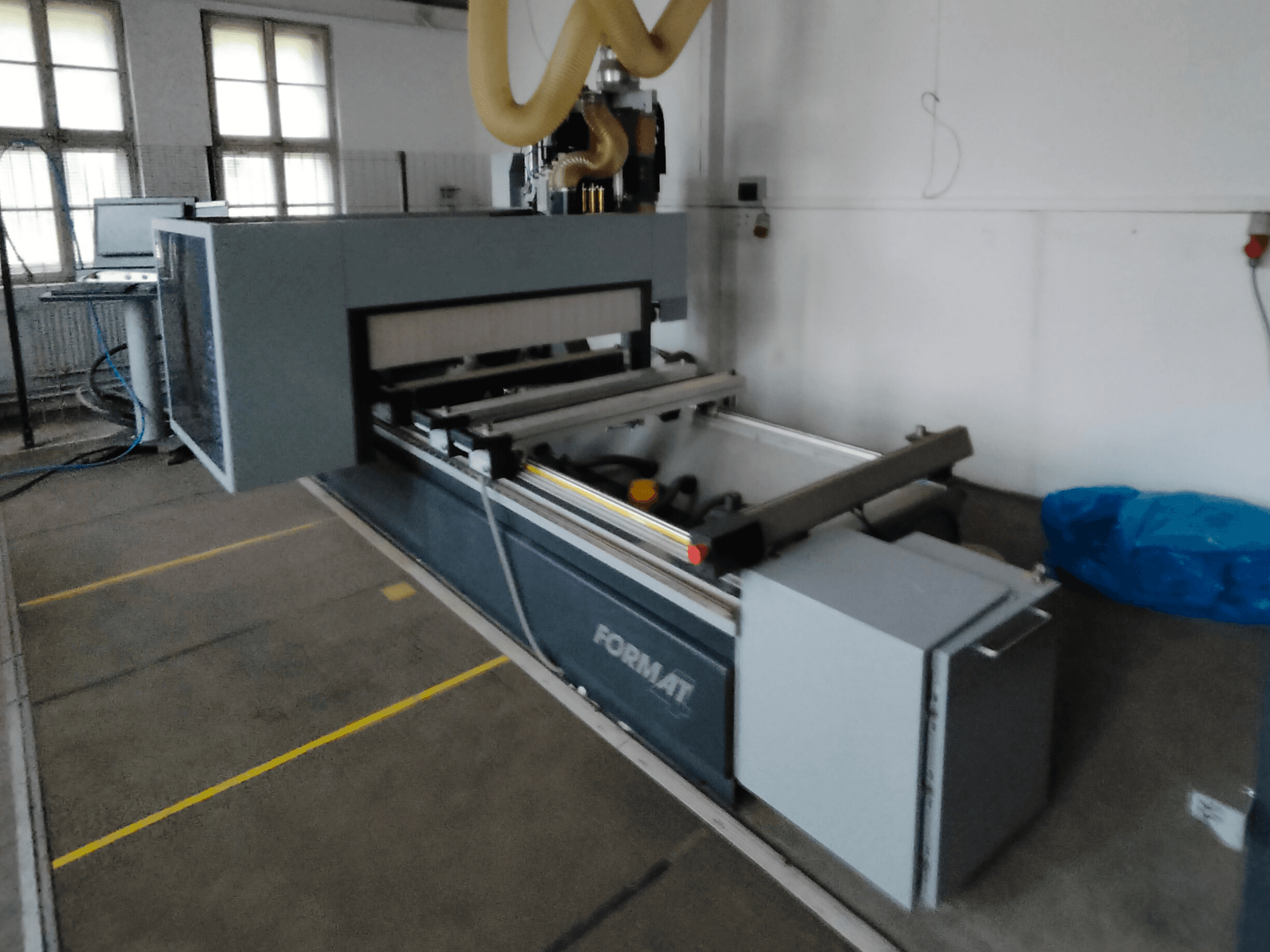 Format CNC staklių su pilku korpusu, kreipiančiaisiais bėgeliais ir matomu valdymo skydeliu vaizdas iš priekio.