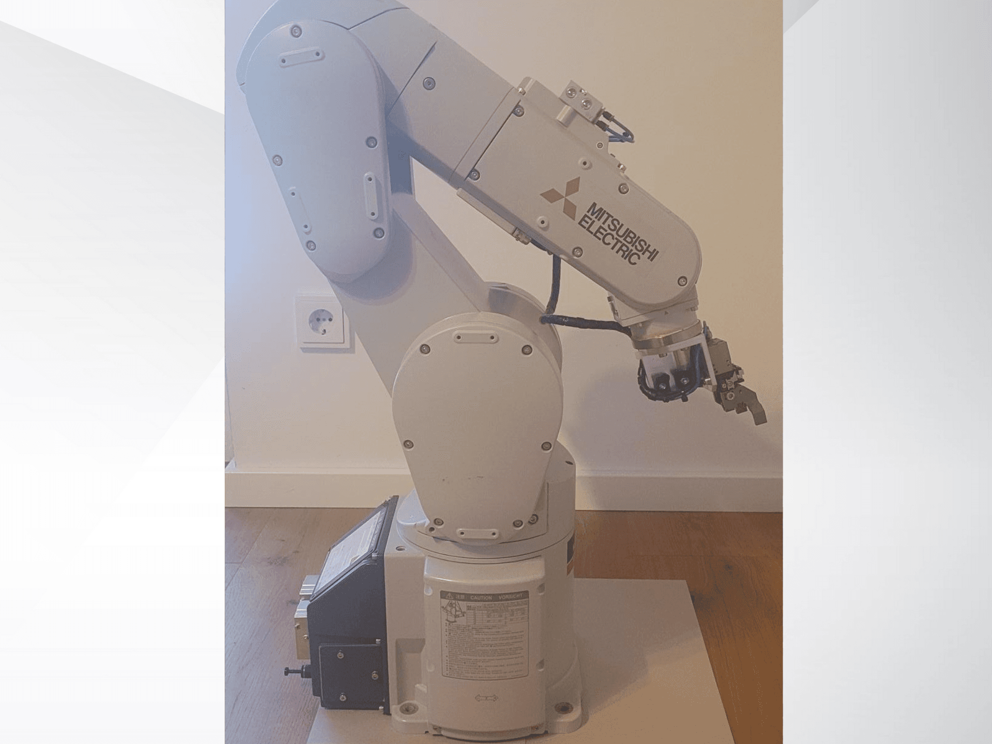 "Mitsubishi Electric" roboto rankos, šoninis vaizdas, su griebtuvu ir išsamiu valdymo skydeliu, esančiu ant pagrindo, kuriame galima nustatyti veikimo parametrus.