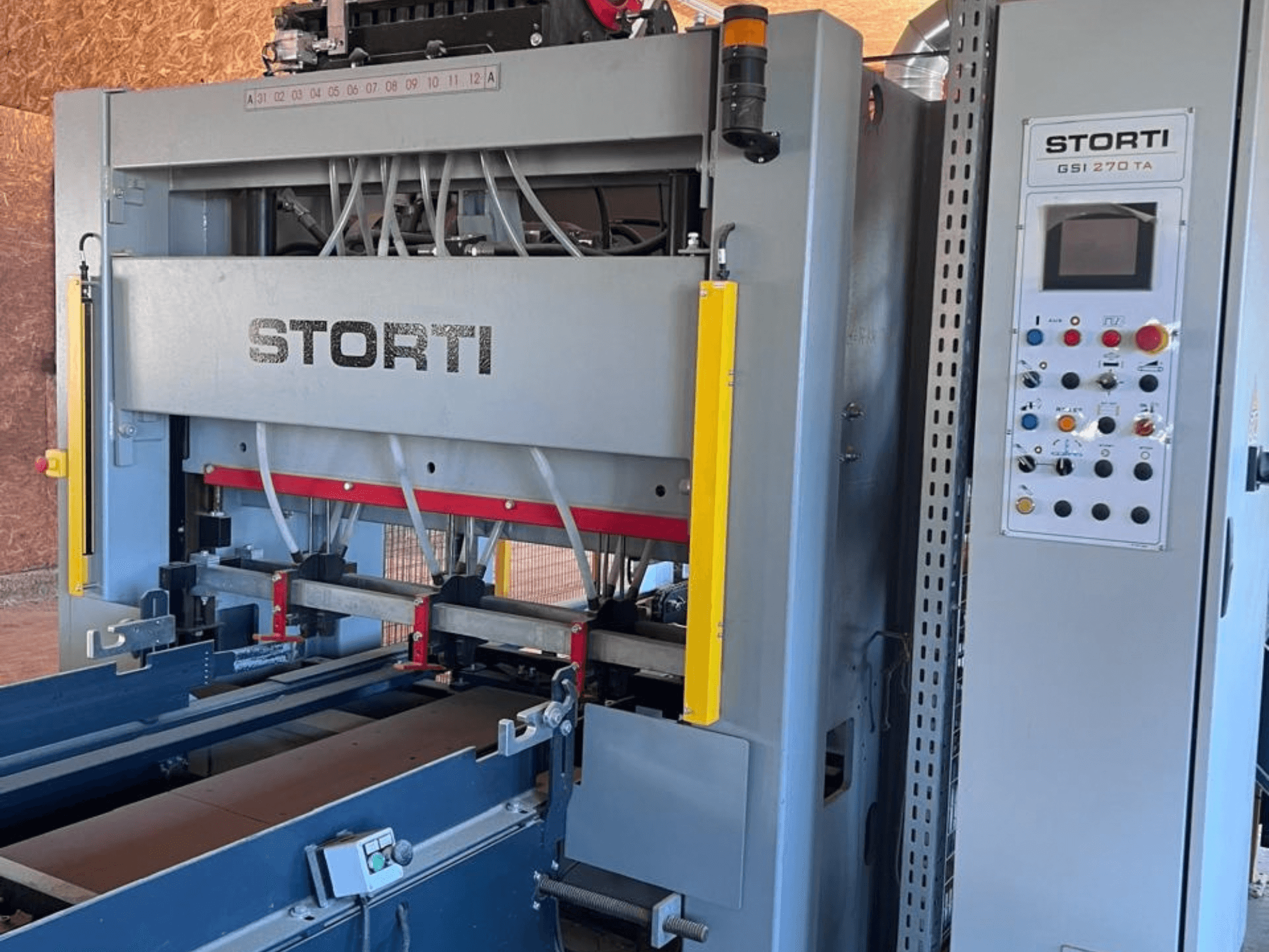 „STORTI GSI 170-270 TA9“ medienos gamybos linija, vaizdas iš priekio, kuriame matomas valdymo pultas ir hidraulinių presų mechanizmai.