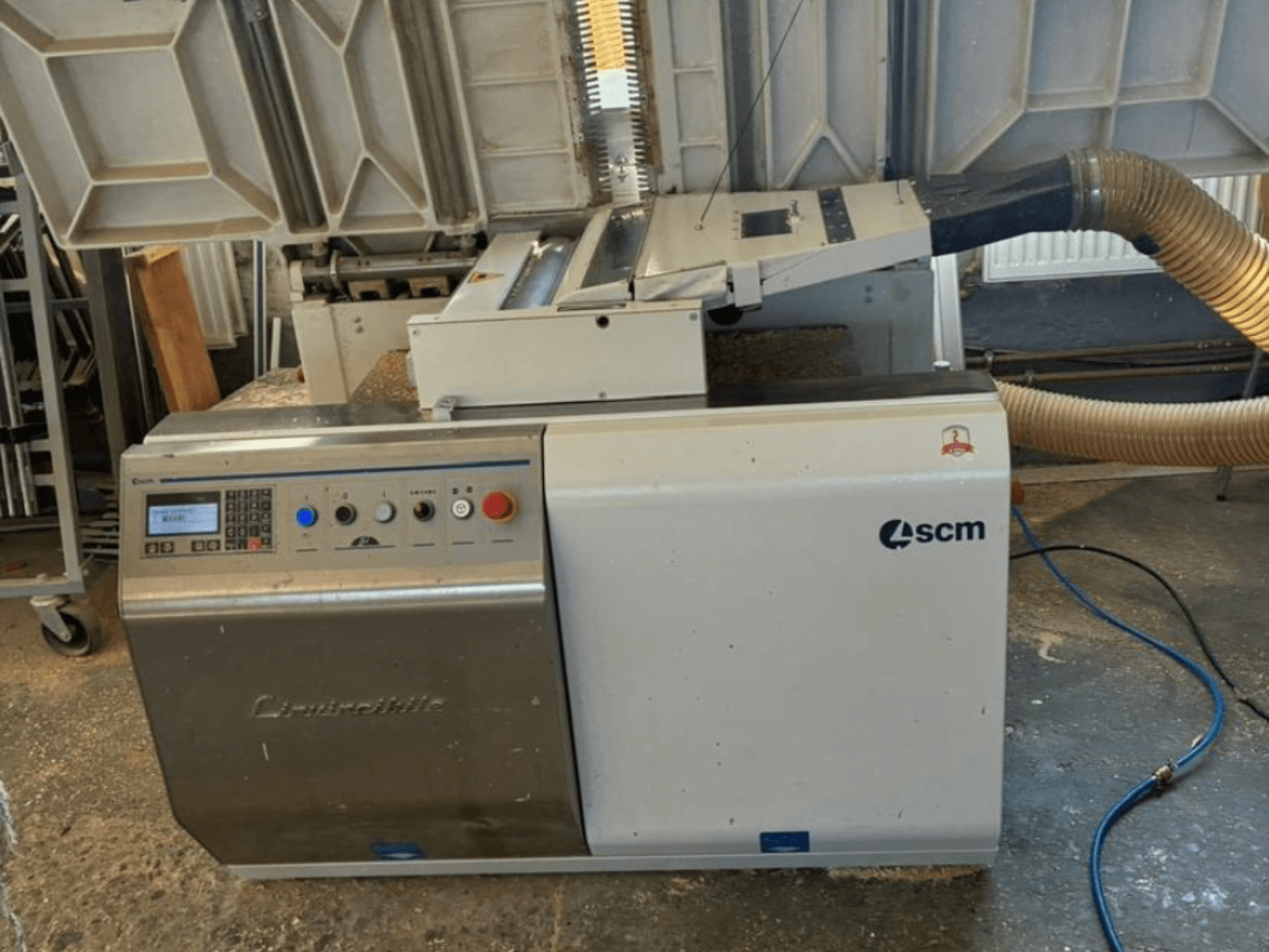 SCM "Centauro" kraštų apklijavimo mašinos priekinis vaizdas, kuriame matyti valdymo skydelis, siurbimo žarna ir atvira darbo zona kraštams klijuoti.