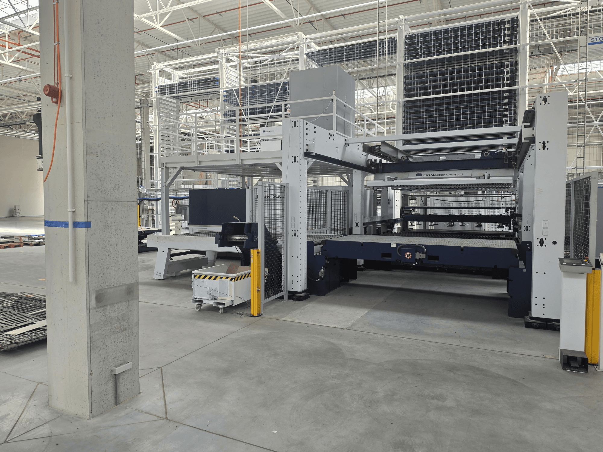 „TRUMPF TruLaser 5030 fiber L76 FMC“ vaizdas iš priekio, kuriame matoma šviesolaidinė pjovimo staklė erdvioje pramoninėje aplinkoje.