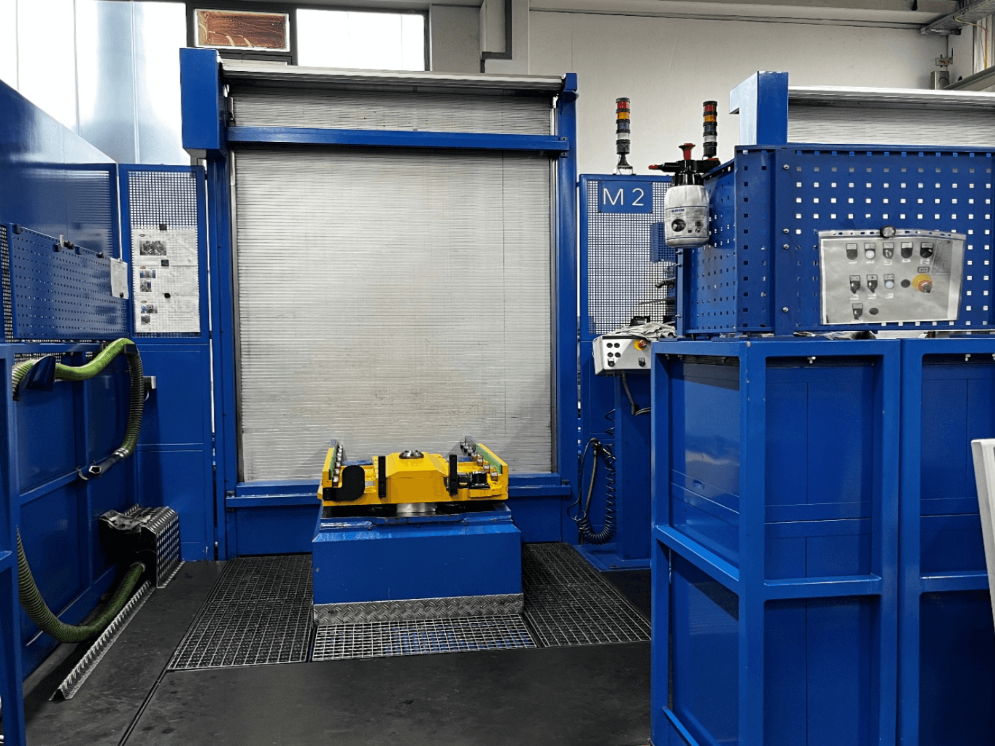 BW MCX750 M2 horizontaliojo apdirbimo centro priekinis vaizdas, kuriame matomos mėlynos plokštės, geltonas darbo stalas ir valdymo blokas.