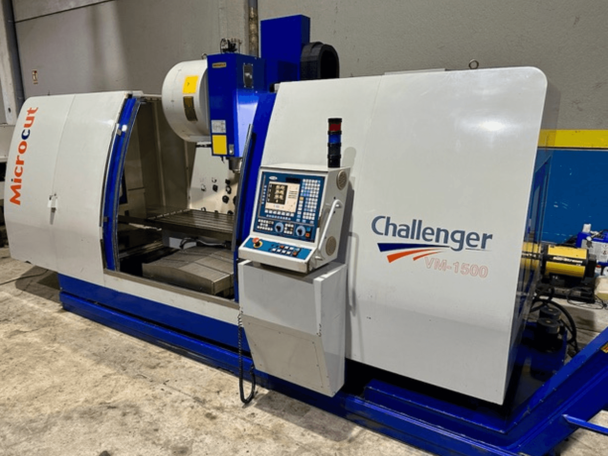 CNC staklės "Microcut Challenger VM-1500", vaizdas iš priekio, valdymo skydelis, darbo vieta ir mėlynas pagrindas.