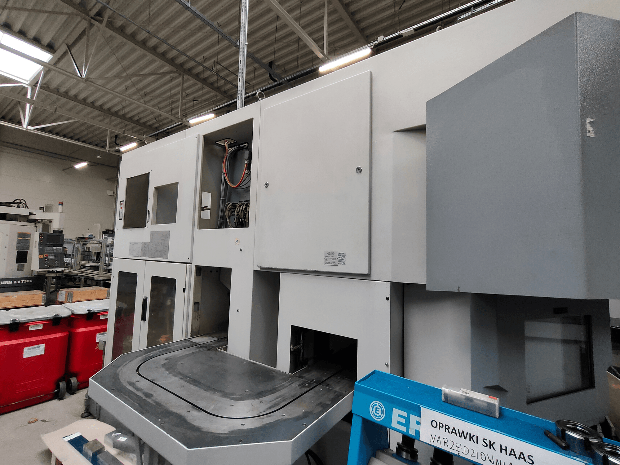 EMAG VSC 250 vertikaliojo tekinimo staklės, parodytos iš šono, su valdymo skydais ir didele darbo zona.