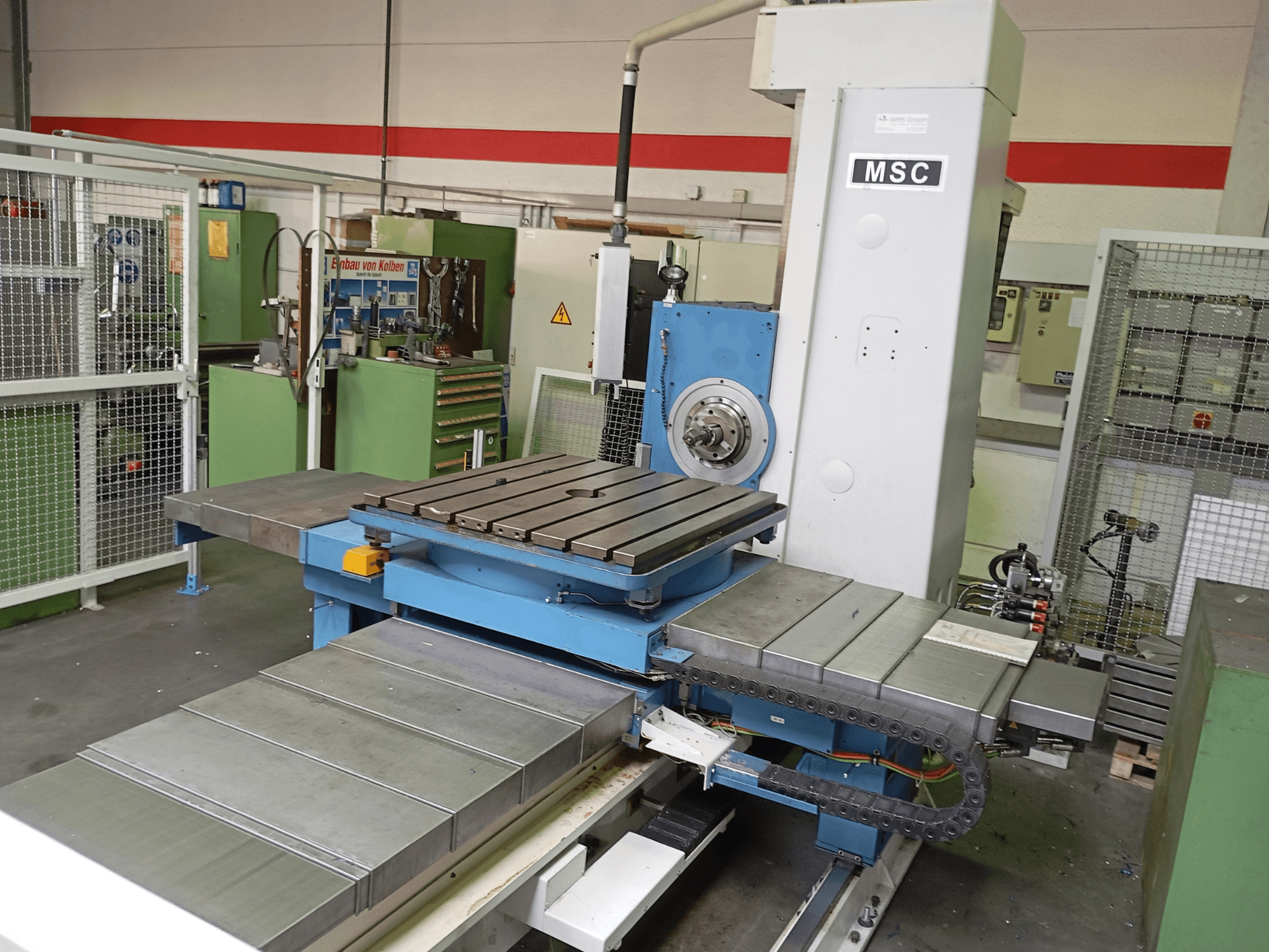 MSC BFT 90/5 TNC 320 ištekinimo staklės, vaizdas iš šono, su metaliniu darbo stalu ir įrankių laikikliu dirbtuvėse.