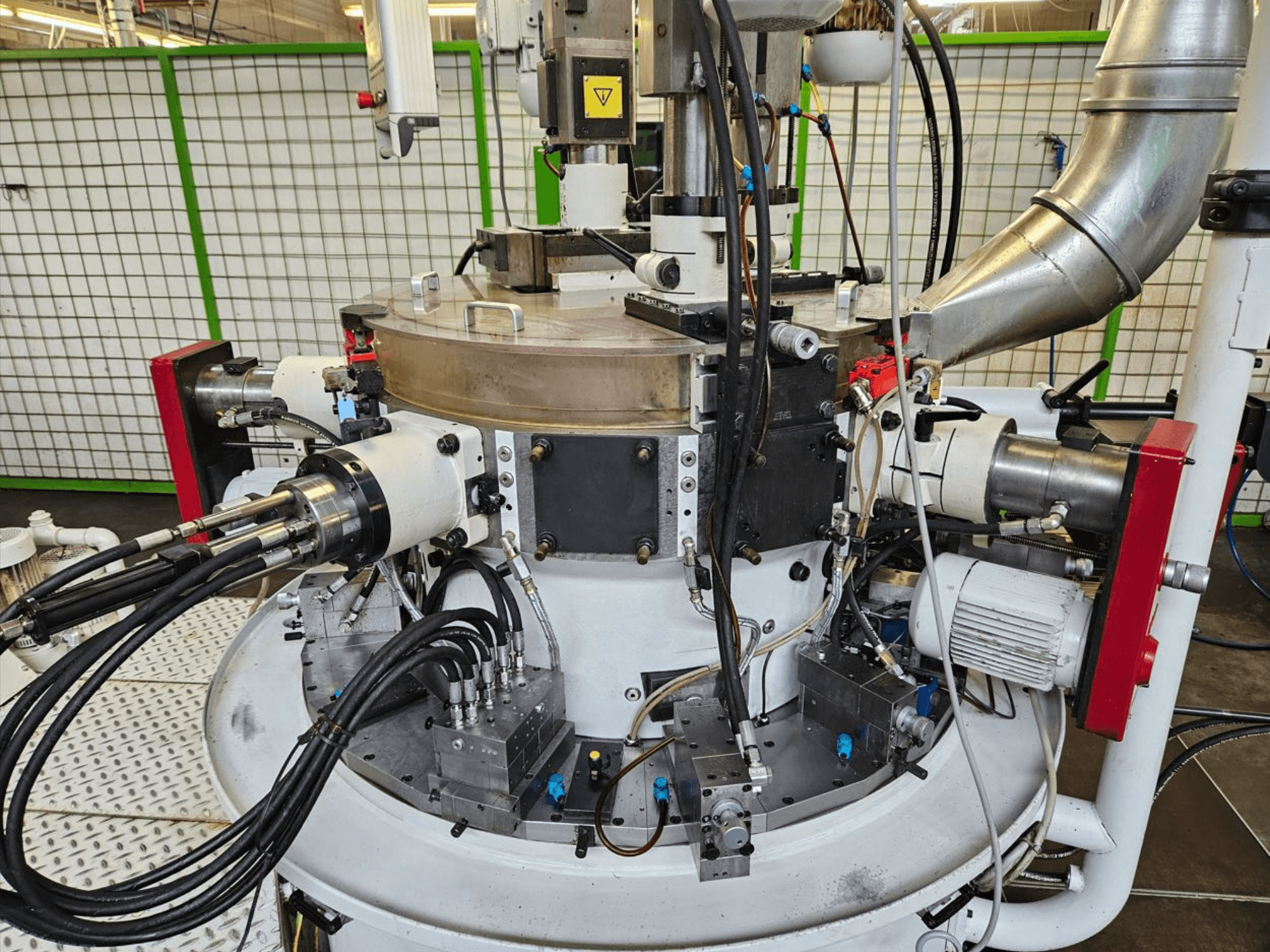 Pramoninės mašinos su hidraulinėmis žarnomis, metaliniais komponentais ir besisukančiu pagrindu vaizdas iš arti. Prekės ženklo nematyti.