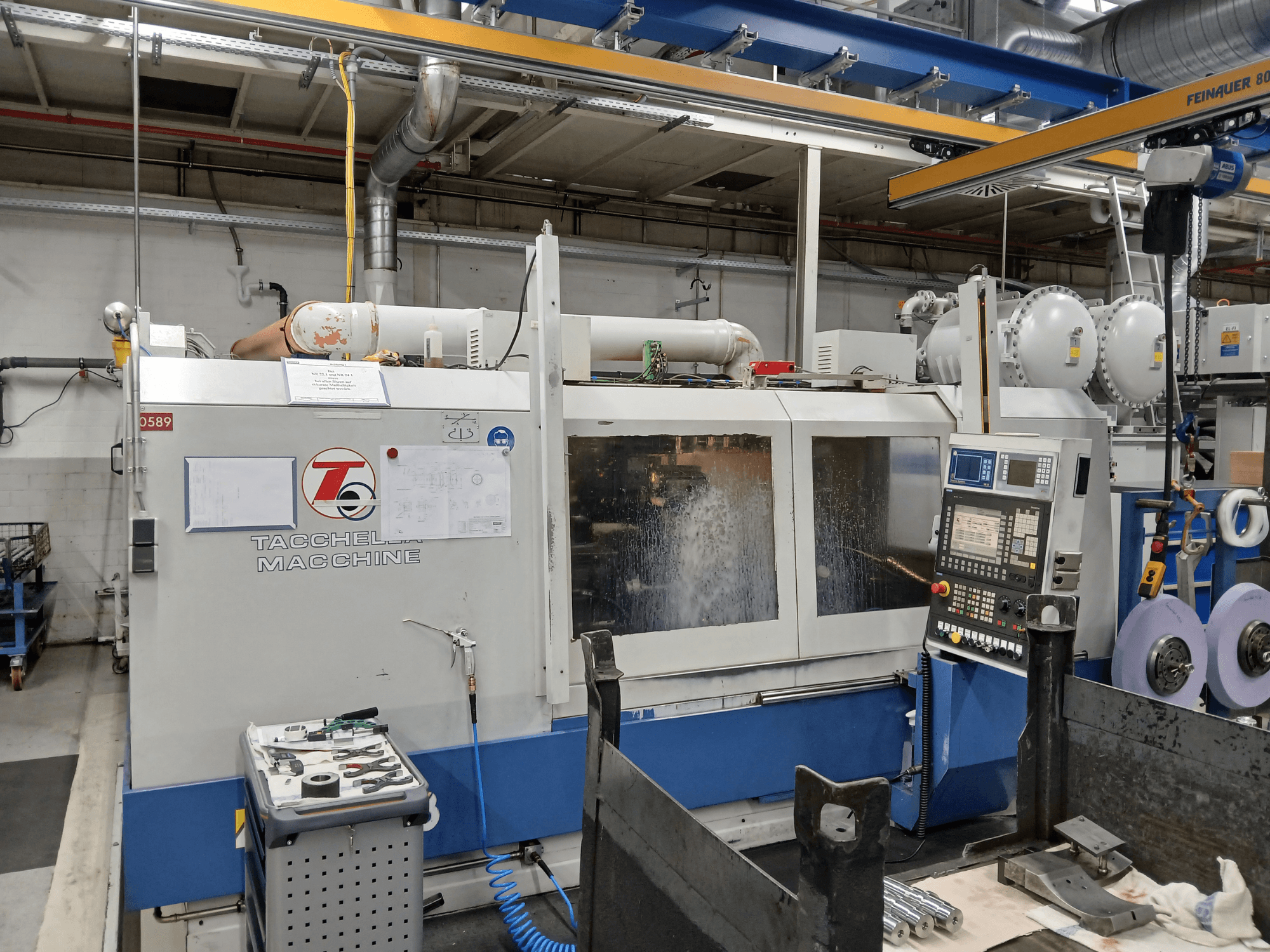 Tacchella apdirbimo centras iš priekio, matomas valdymo skydelis ir įrankiai. Darbo metu purškiamas vandens aušinimo skystis.