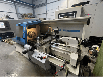 CNC tekinimo staklės DUS 400 ti iš priekio, su valdymo pultu, įrankių laikikliu ir apšviesta darbo vieta.