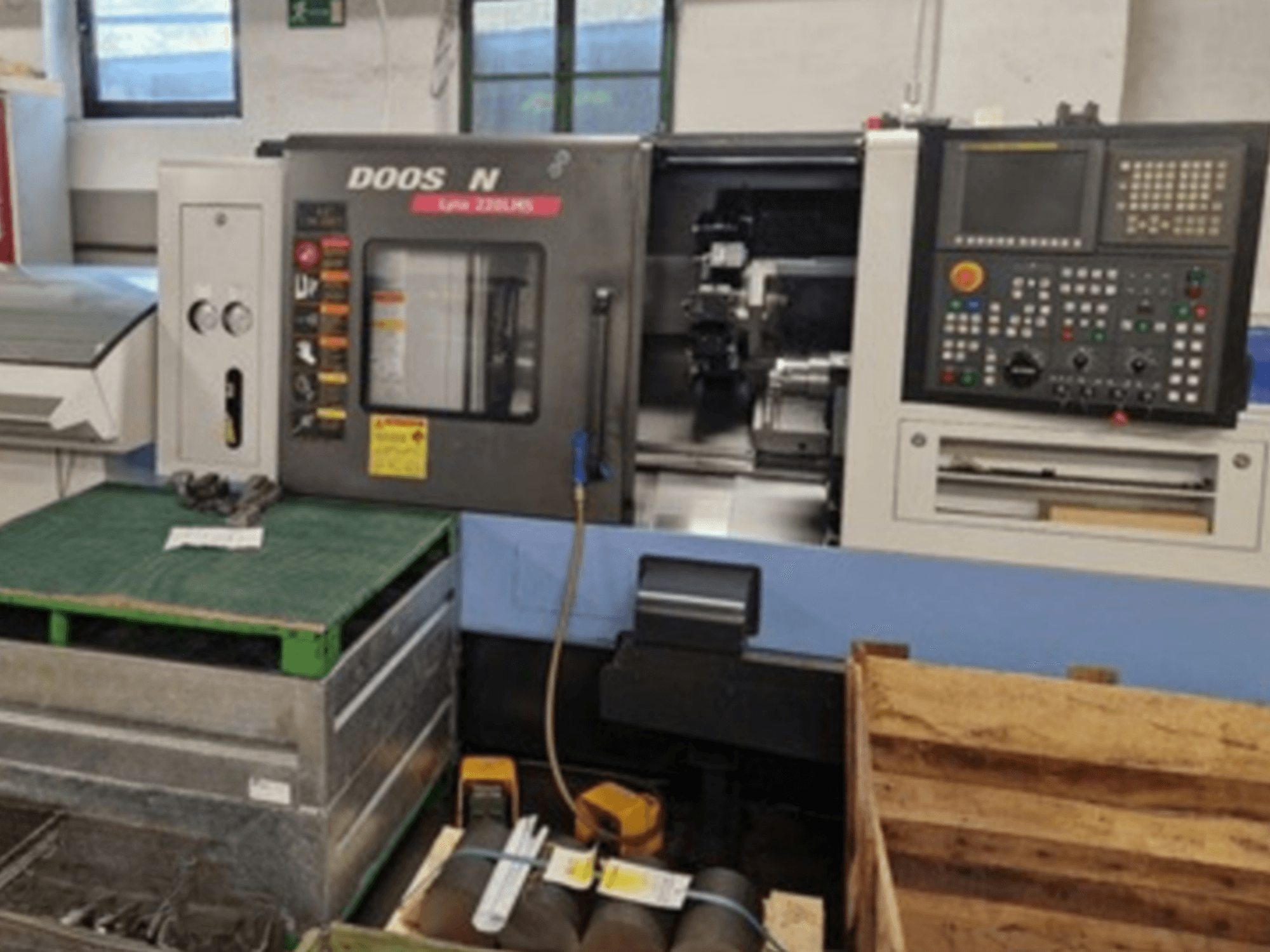 DOOSAN Lyax 220 LMS horizontaliojo tekinimo staklės iš priekio, matomas valdymo skydelis, įrankiai ir darbo vieta.