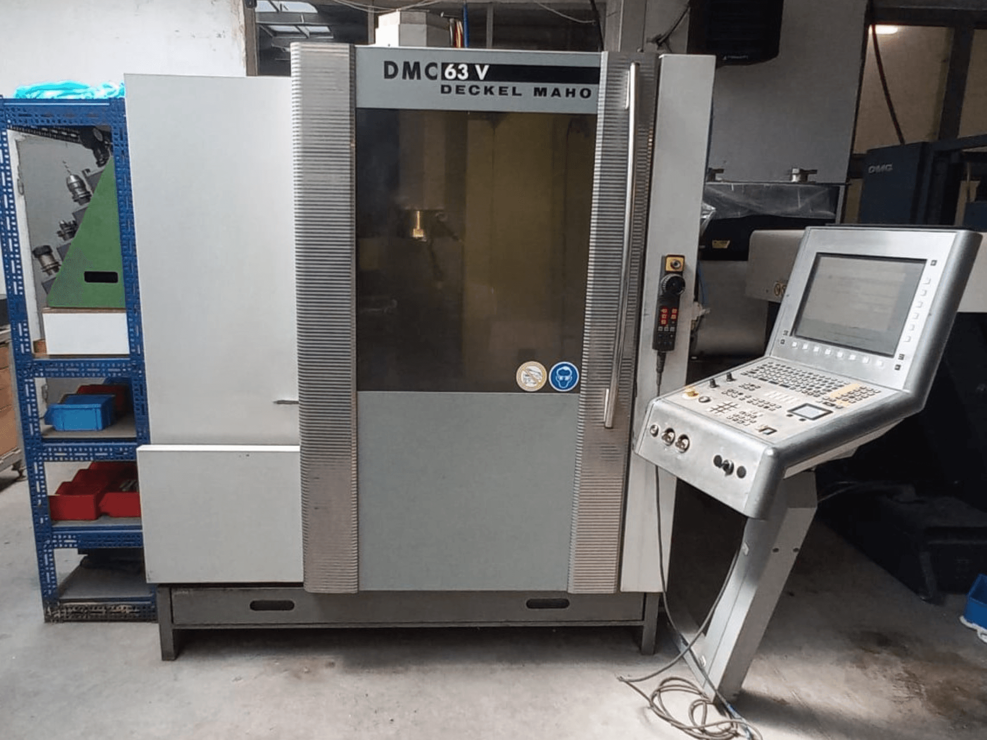 DMG DECKEL MAHO DMC 63V vertikaliojo apdirbimo centro vaizdas iš priekio su valdymo pultu ir matoma darbo zona.