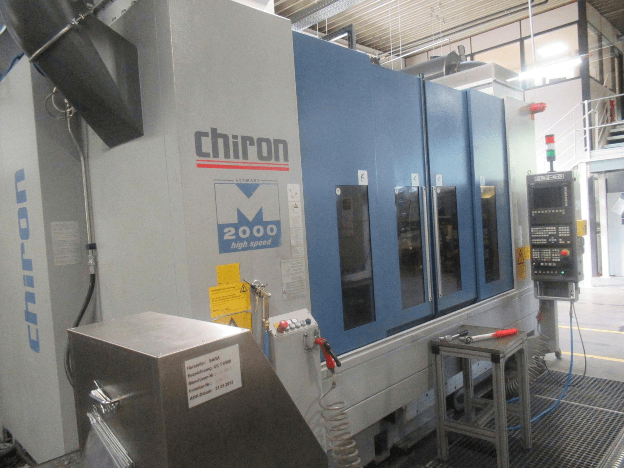 Vertikalus apdirbimo centras „CHIRON Mill 2000“, vaizdas iš priekio su valdymo skydeliu, mėlynos spalvos dizainas ir matomos greitojo veikimo funkcijos.