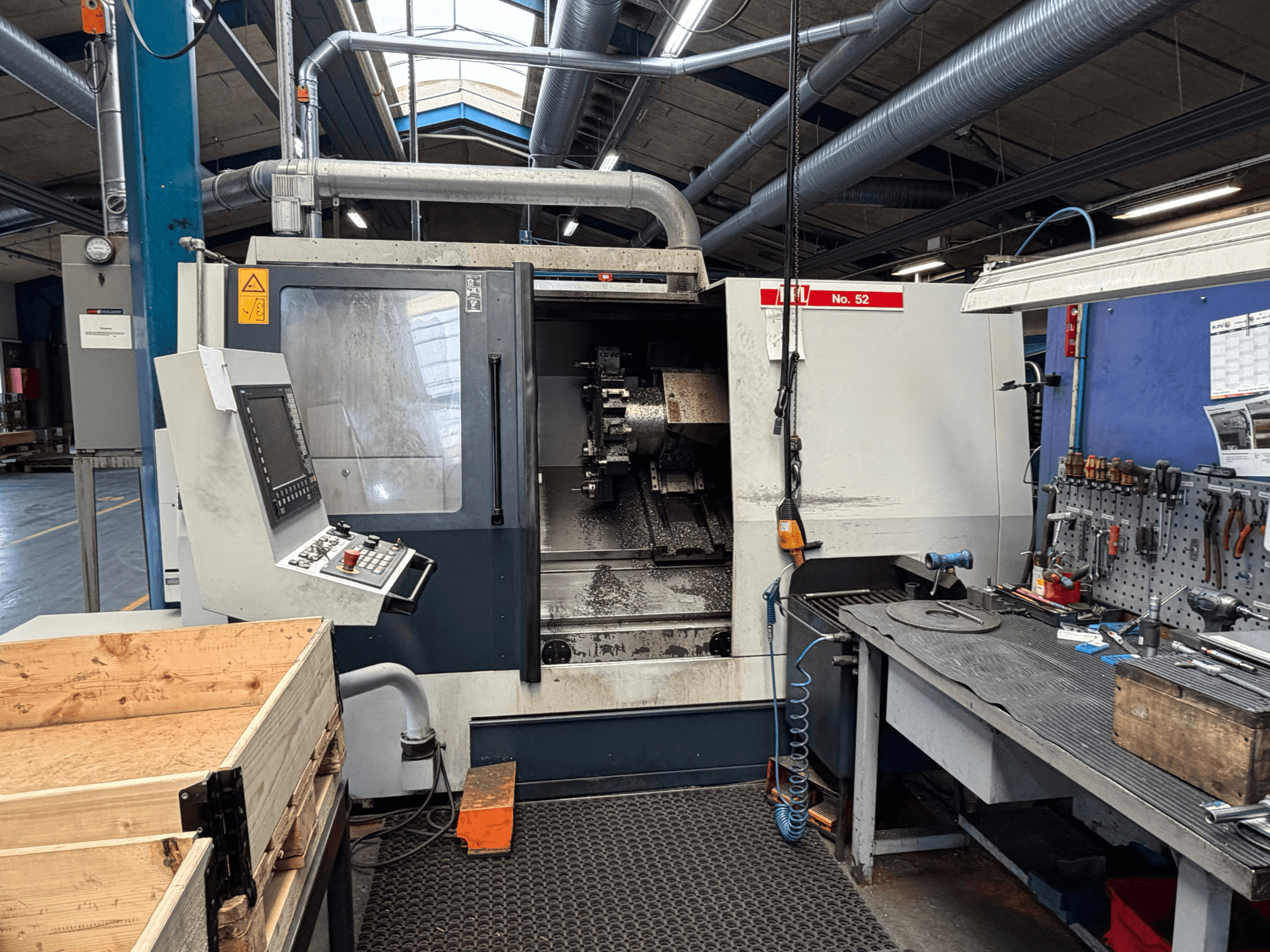 Horizontaliosios tekinimo staklės SPINNER TC800 110 SMCY, žiūrint iš priekio, su valdymo pultu ir šalia esančia darbo vieta.