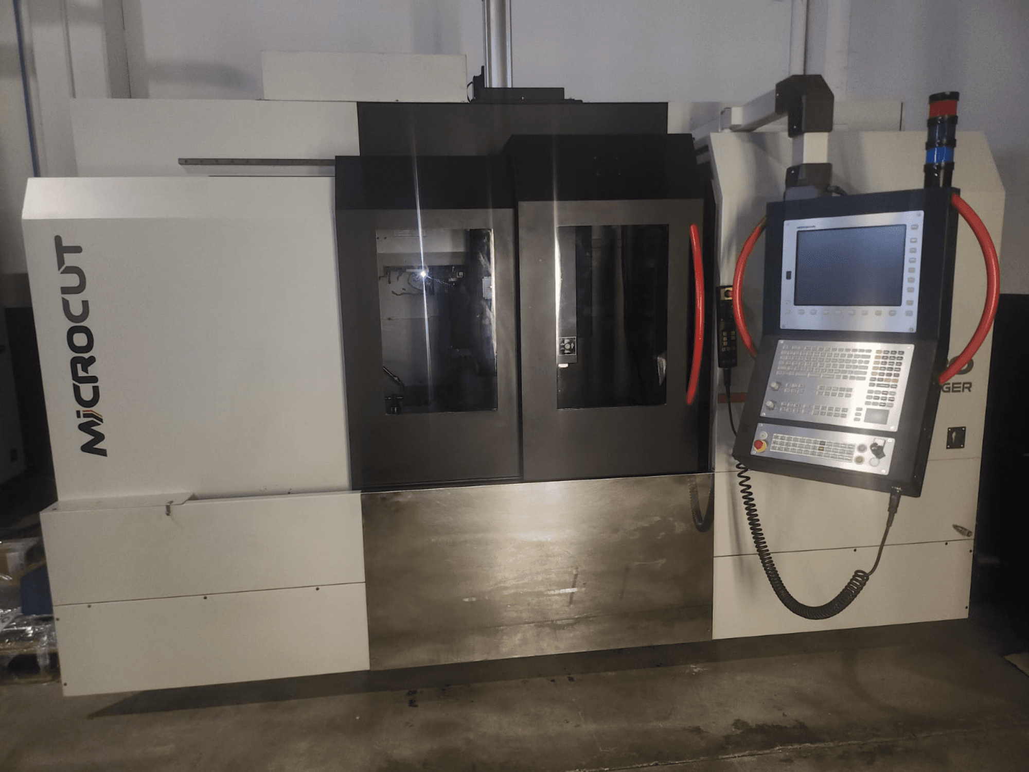 "Microcut CNC" staklės, žiūrint iš priekio; valdymo skydelis, du langai, pramoninis dizainas ir metalinė apdaila.