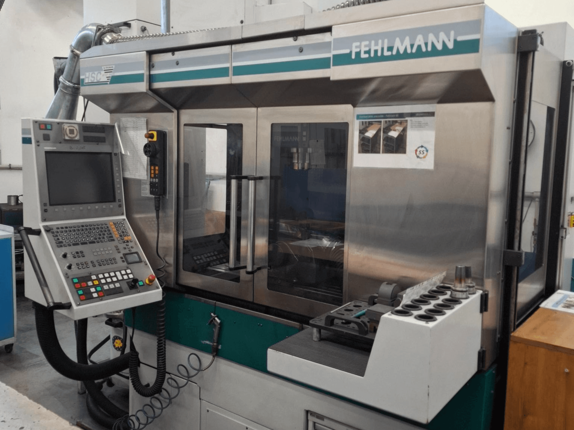 Fehlmann HSC 20 CNC staklės, vaizdas iš priekio, valdymo skydelis, metalinis korpusas ir įrankių laikiklis su keliais lizdais.