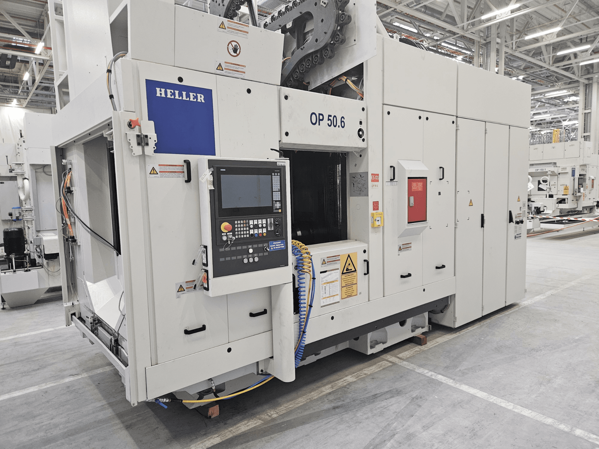 "Heller OP 50.6" apdirbimo centras, vaizdas iš priekio, gamykloje matomas valdymo skydelis, įspėjamosios etiketės ir žarnos.