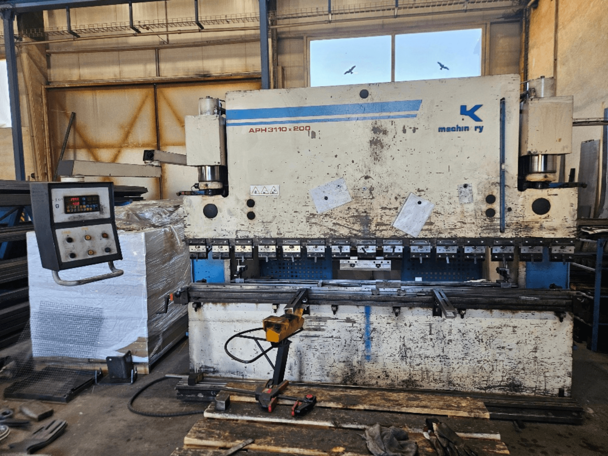 "Baykal APH 3110x200" presas dirbtuvėse, vaizdas iš priekio, matomas valdymo skydelis, metalo lakštai ir įrankiai.