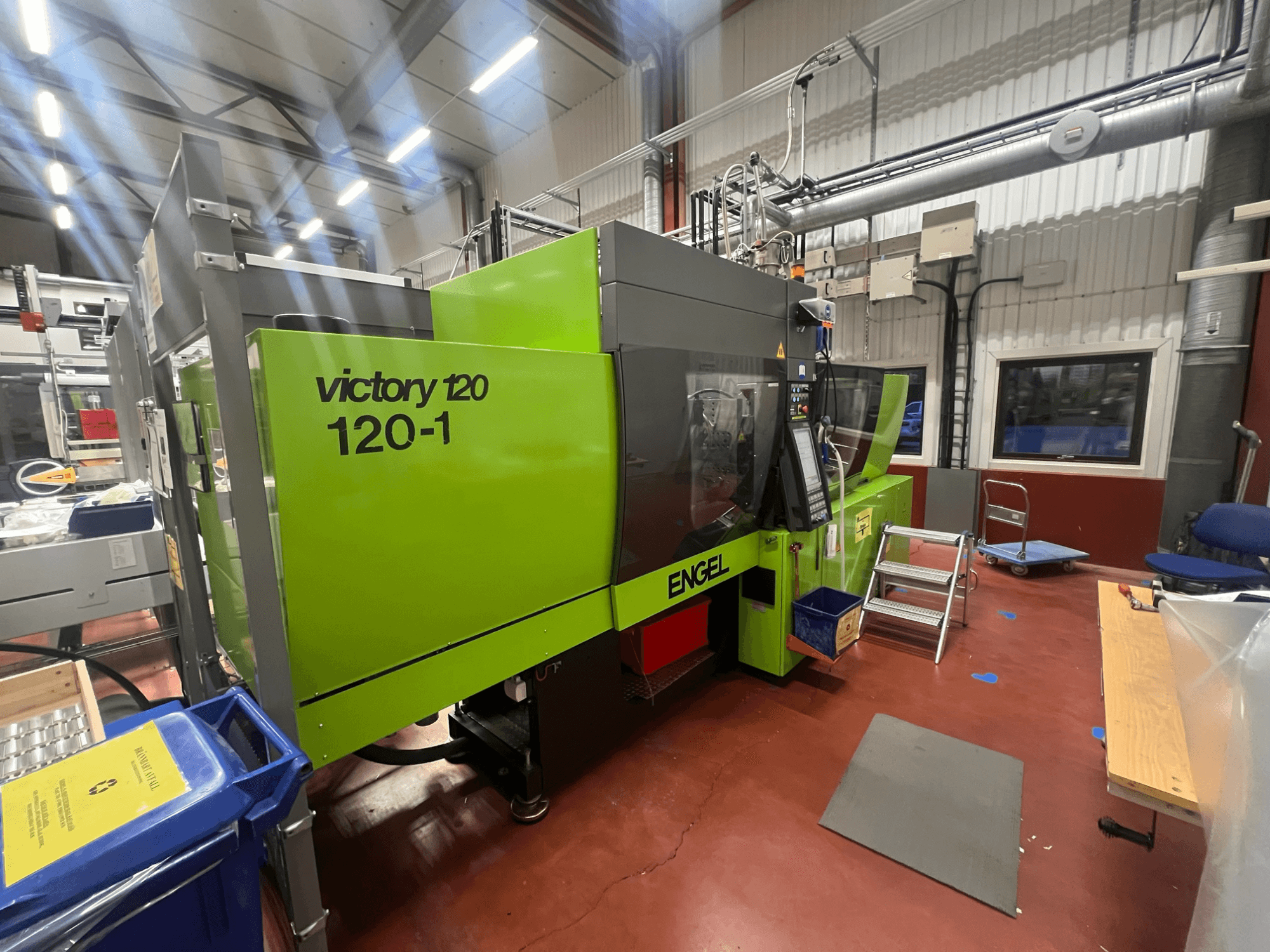 Žalios spalvos ENGEL Victory 120-1 įpurškimo liejimo mašina, vaizdas iš priekio, su valdymo skydeliu ir pakopomis, pramoninėje aplinkoje.