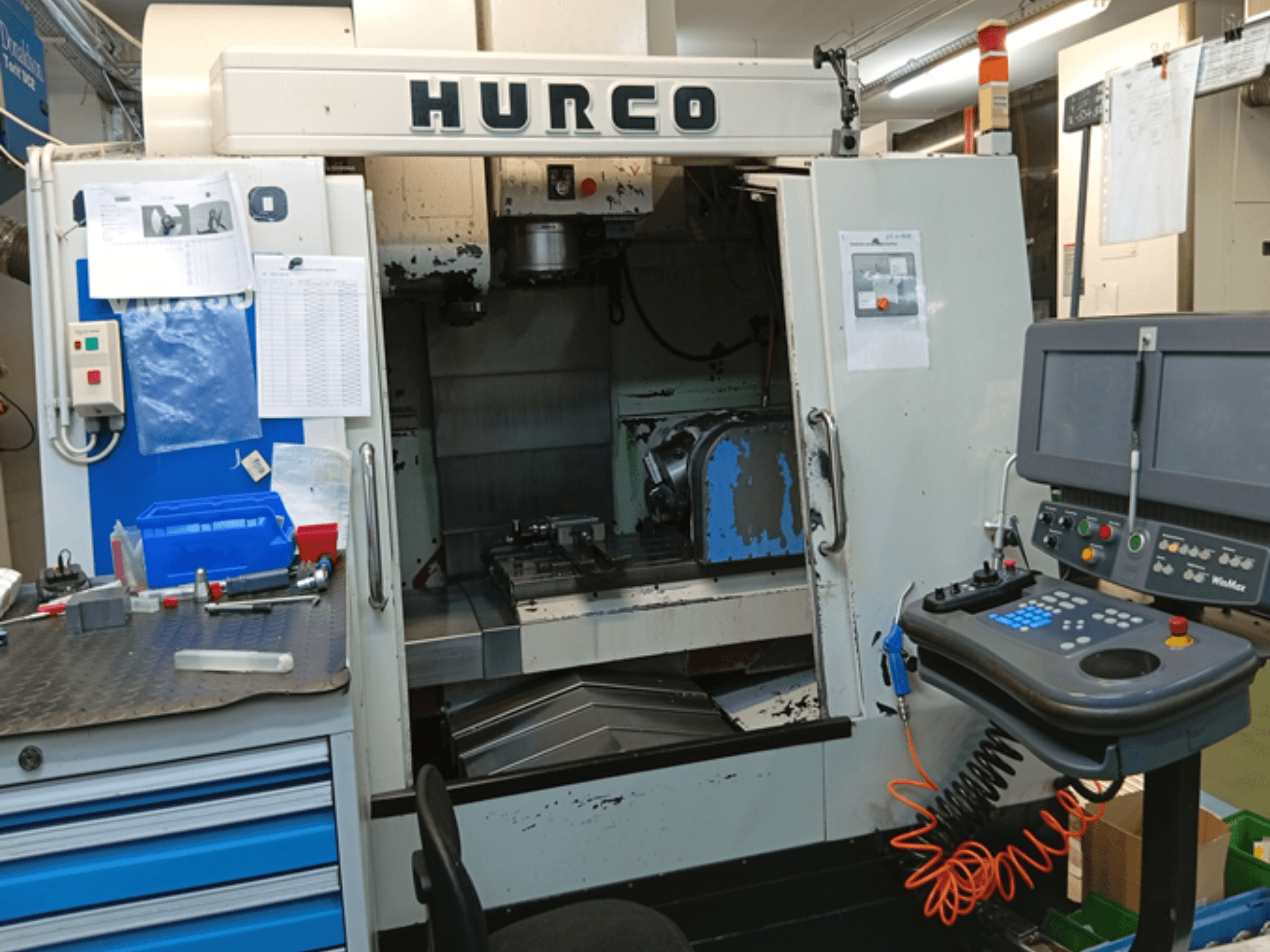 Hurco VMX 30T vertikalusis apdirbimo centras, vaizdas iš priekio, kuriame matomas valdymo skydelis, darbo vieta ir iš dalies atidarytos durys.