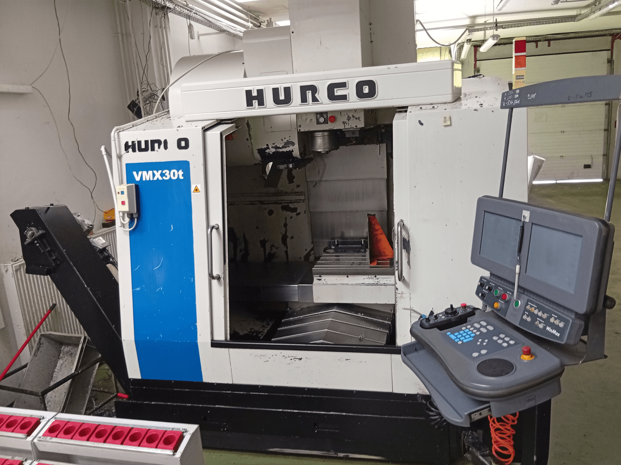 Vertikalusis apdirbimo centras „Hurco VMX 30T“, vaizdas iš priekio, kuriame matomas valdymo pultas, suklio zona ir apdirbimo stalas.