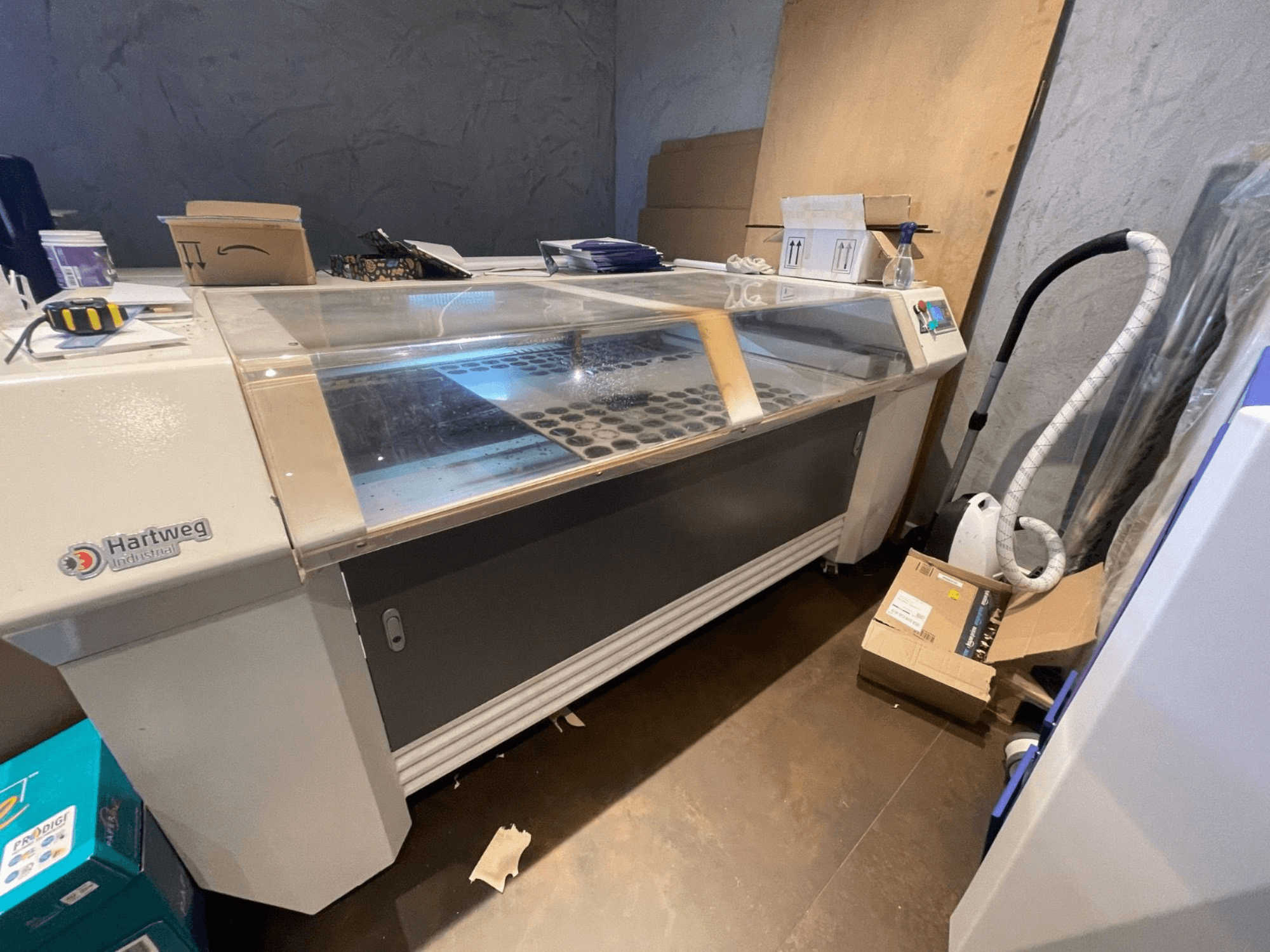 CO2 lazerinio pjaustymo staklės Bodor CL-1610XUF iš šono, rodoma darbo zona su medžiagų lizdais ir valdymo skydeliu.