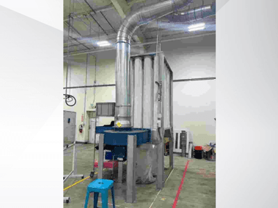 Didelė pramoninė vėdinimo sistema, vaizdas iš priekio, su blizgančiais metaliniais ortakiais ir mėlynu pagrindu, įrengta erdviame sandėlyje.