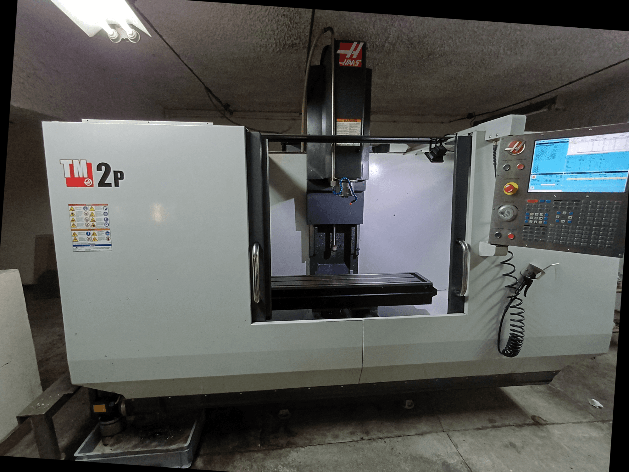 HAAS TM-2P vertikalusis apdirbimo centras, priekinis vaizdas, kuriame matyti valdymo skydelis, suklio galvutė ir staklių lova.