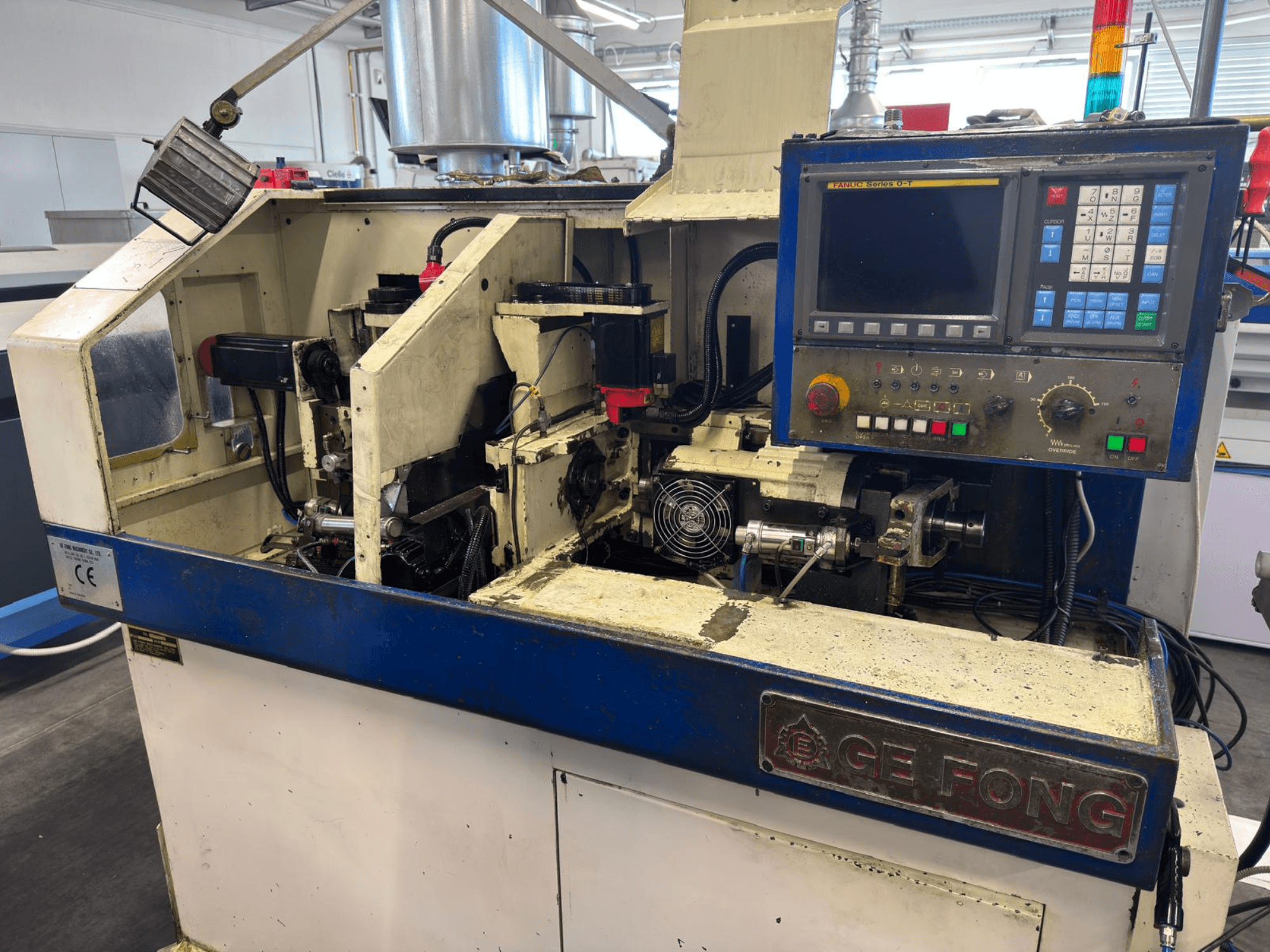 GE FONG pramoninės mašinos priekinis vaizdas, kuriame matyti vidiniai komponentai, valdymo skydelis ir darbinės dalys.