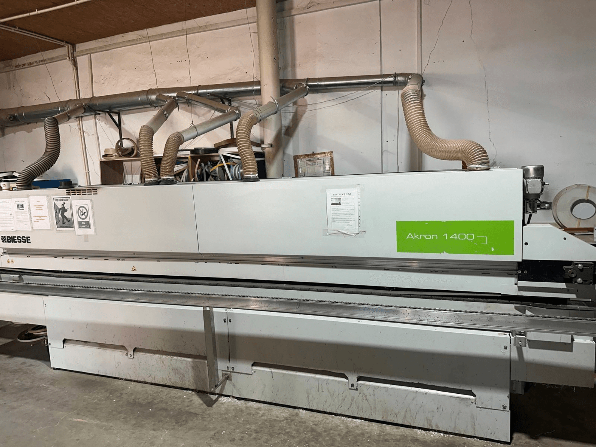 BIESSE „Akron 1440 A“ kraštų apdirbimo staklės, vaizdas iš šono, su ventiliacijos vamzdžiais, valdymo pultu ir eksploatacijos lipdukais.
