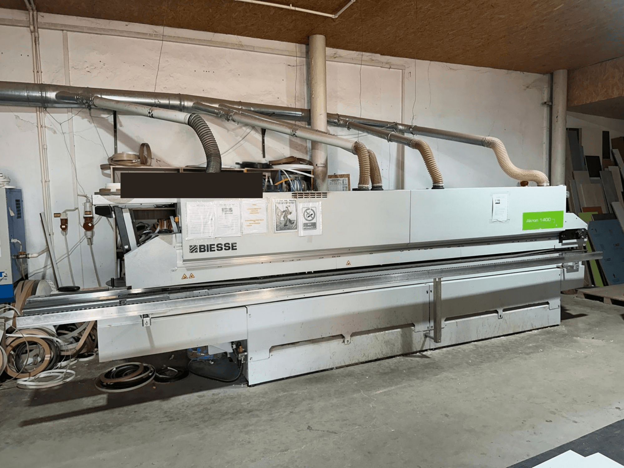 BIESSE AKRON 1440 A kraštų apdirbimo staklės, vaizdas iš priekio, kuriame matomas valdymo skydelis ir dulkių surinkimo įranga dirbtuvės aplinkoje.