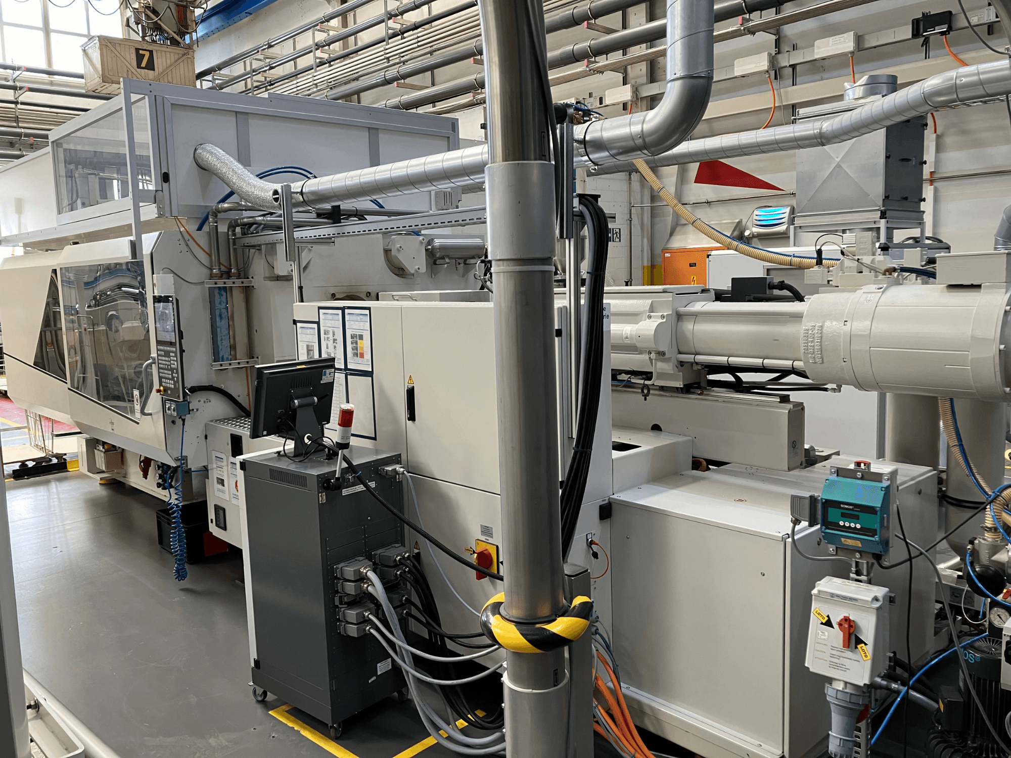 Pramoninės mašinos su valdymo skydeliu, vaizdas iš priekio, vamzdžiai, elektros komponentai ir saugos elementai.